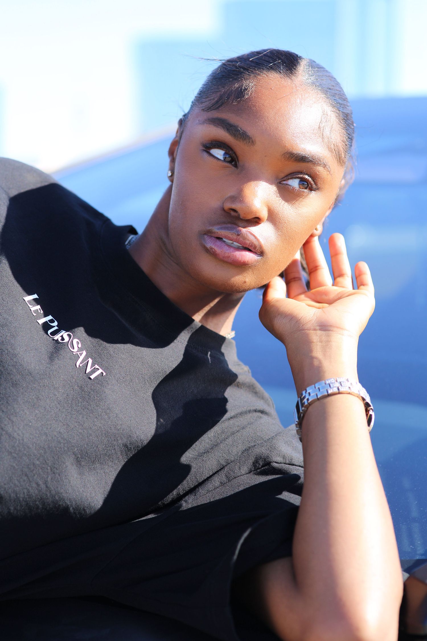 Portrait of someone wearing a black sweatshirt and silver bracelet against a blue background.