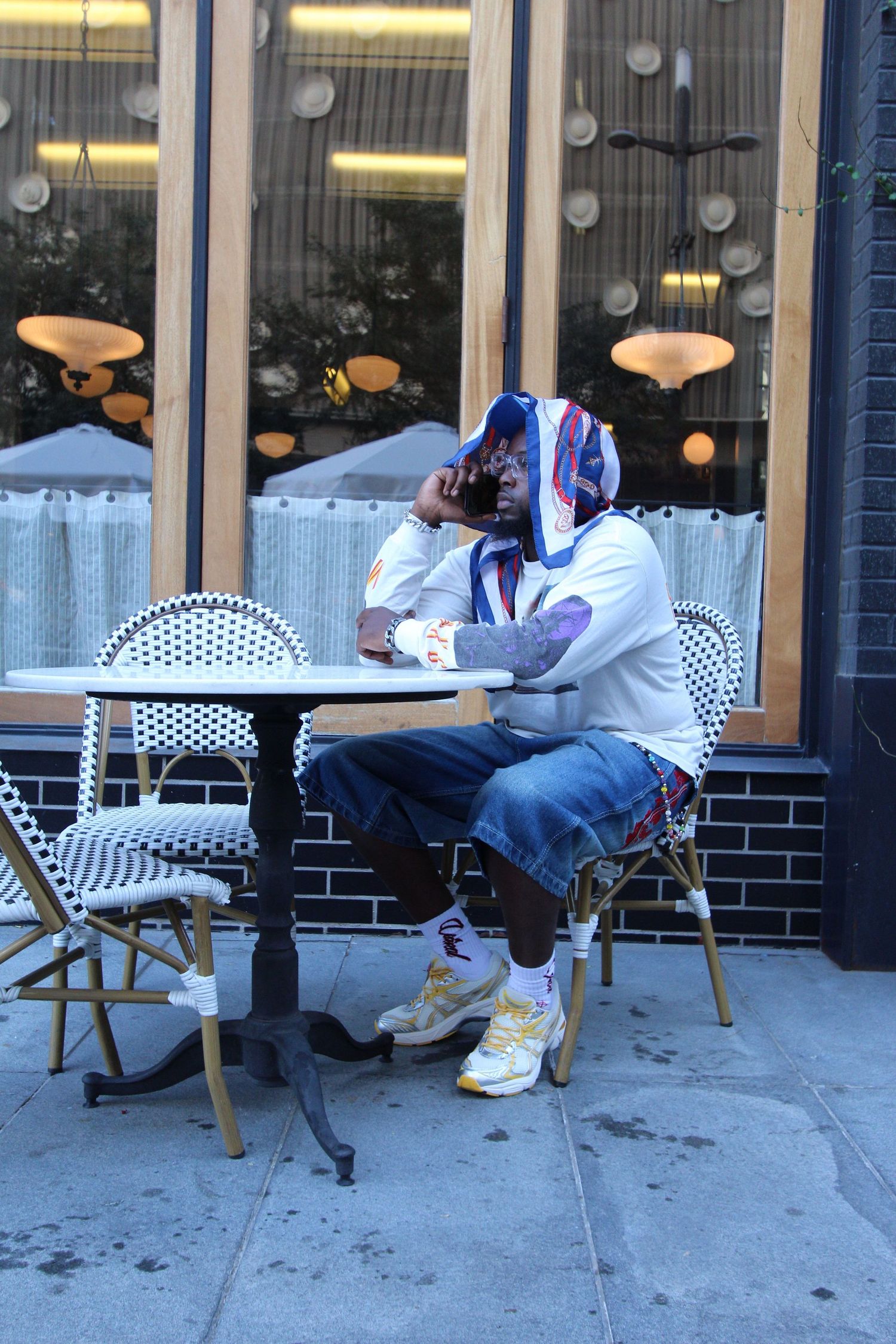 A sequence of four images showing someone reclining in a bistro chair on a sidewalk outside a storefront.