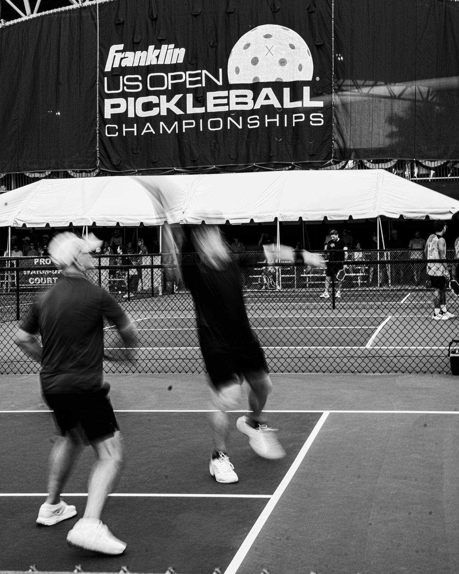 Black and white photo of players competing at the Franklin US Open Pickleball Championships outdoor court.