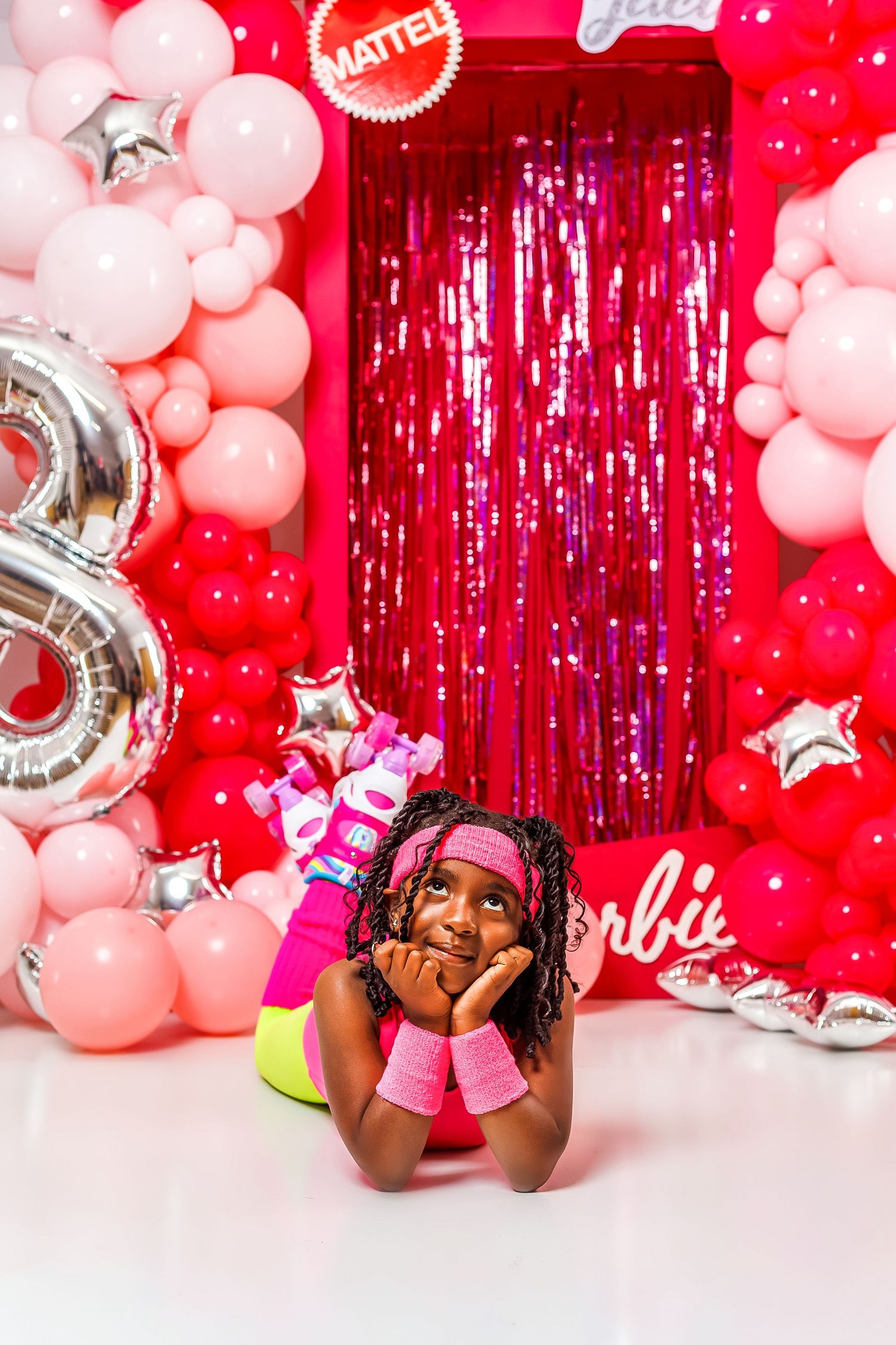Young girl in pink Barbie-themed outfit posing with balloons and decorations for 8th birthday.