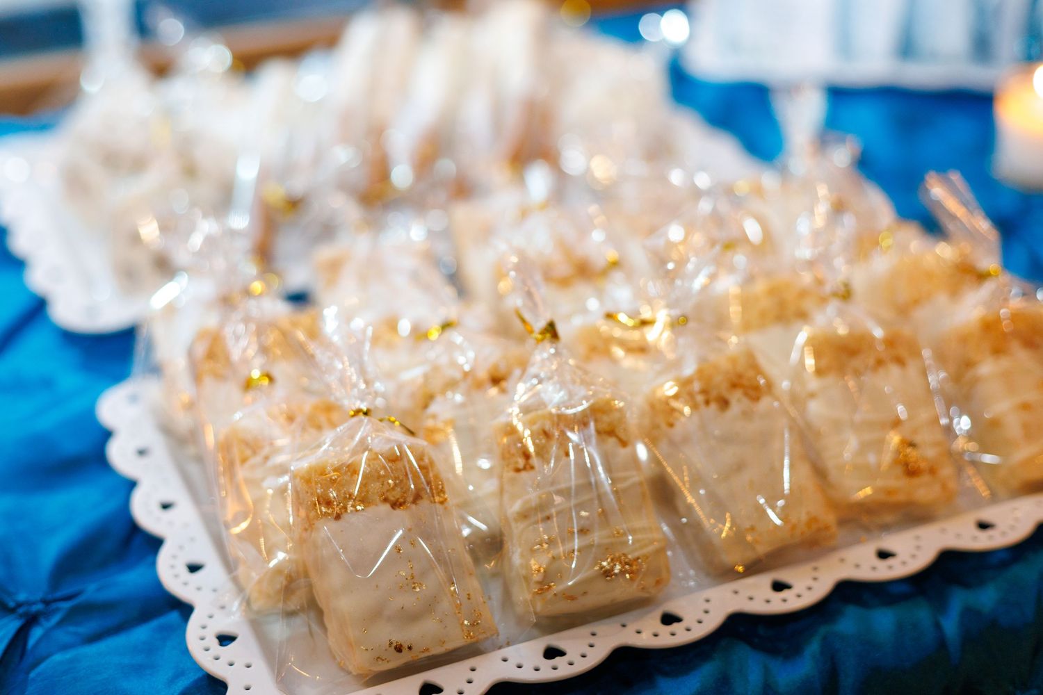 Elegant gold-wrapped dessert favors arranged on a white decorative tray at a celebration event.