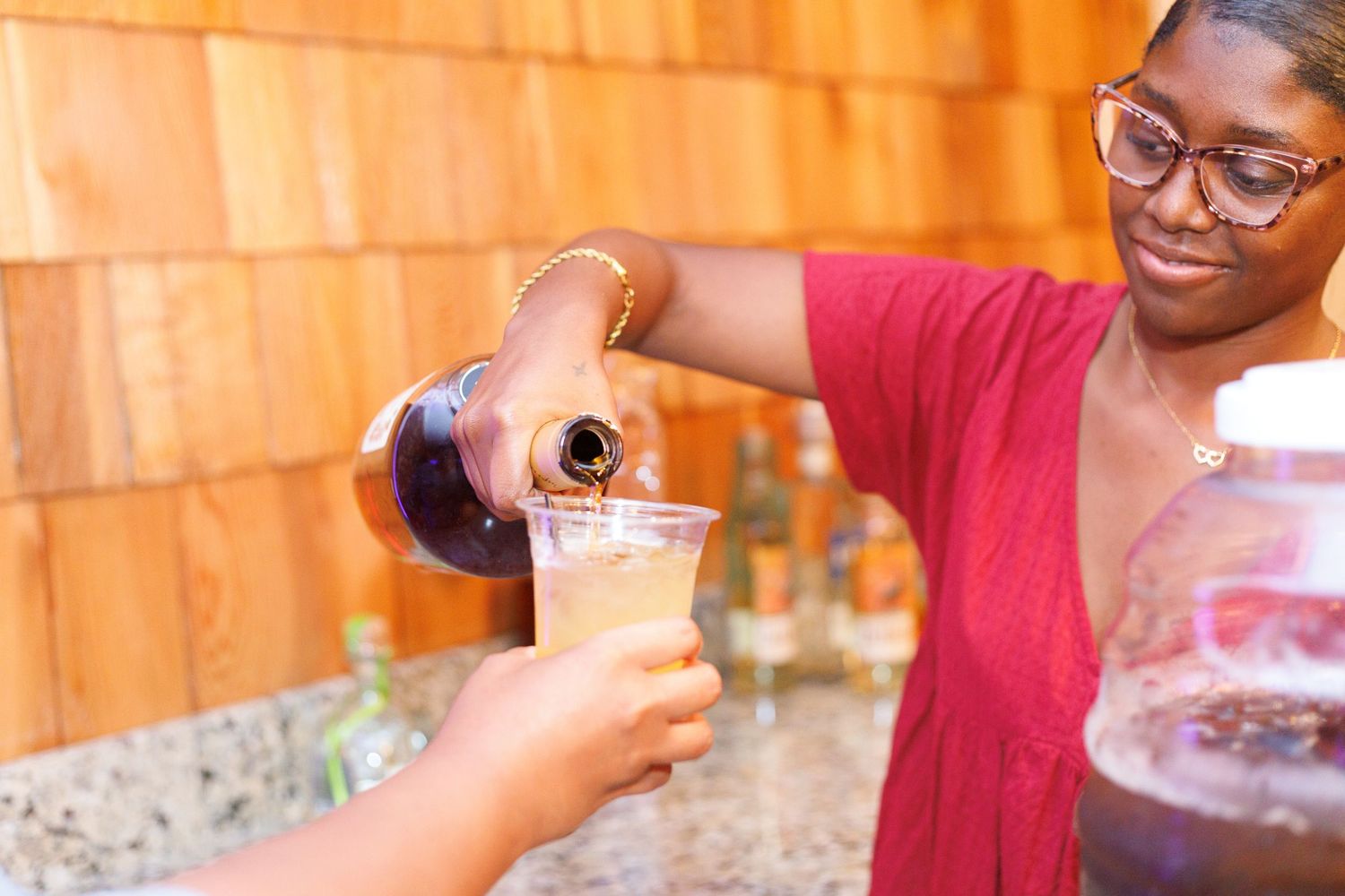 Bartender pouring champagne into a cup at an outdoor wedding reception bar.