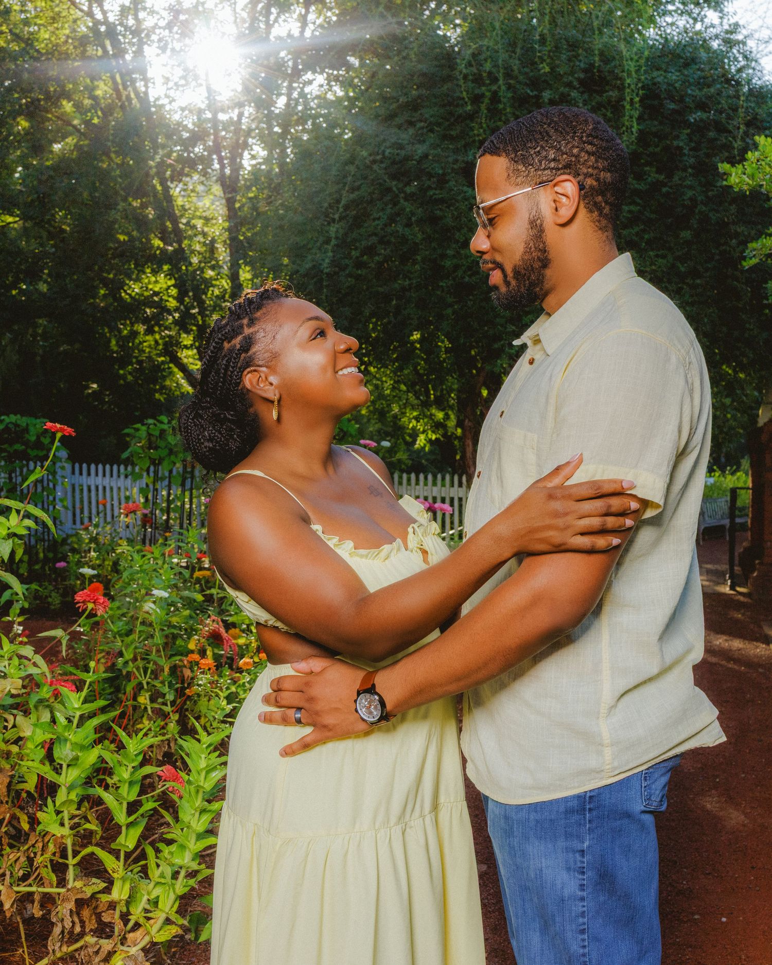 Couple in casual summer attire sharing a romantic moment in a sunlit garden.