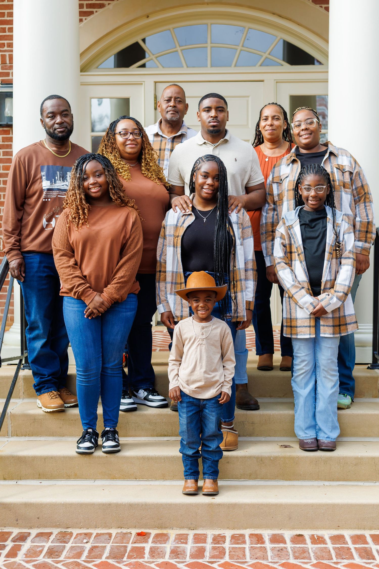 Large family portrait on brick steps with young boy in cowboy hat standing in front.
