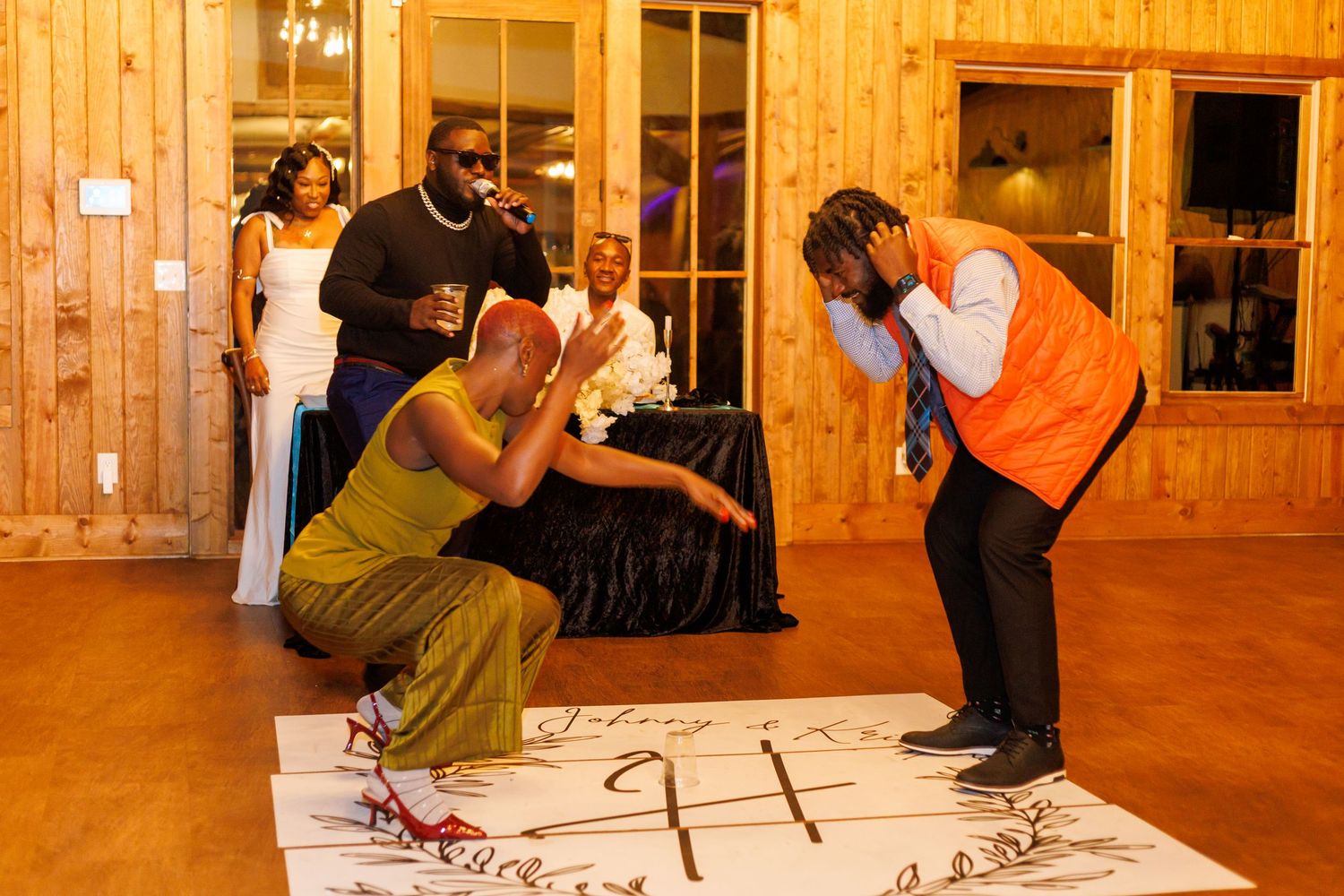 Wedding guests dancing and celebrating on a personalized dance floor at a rustic reception.