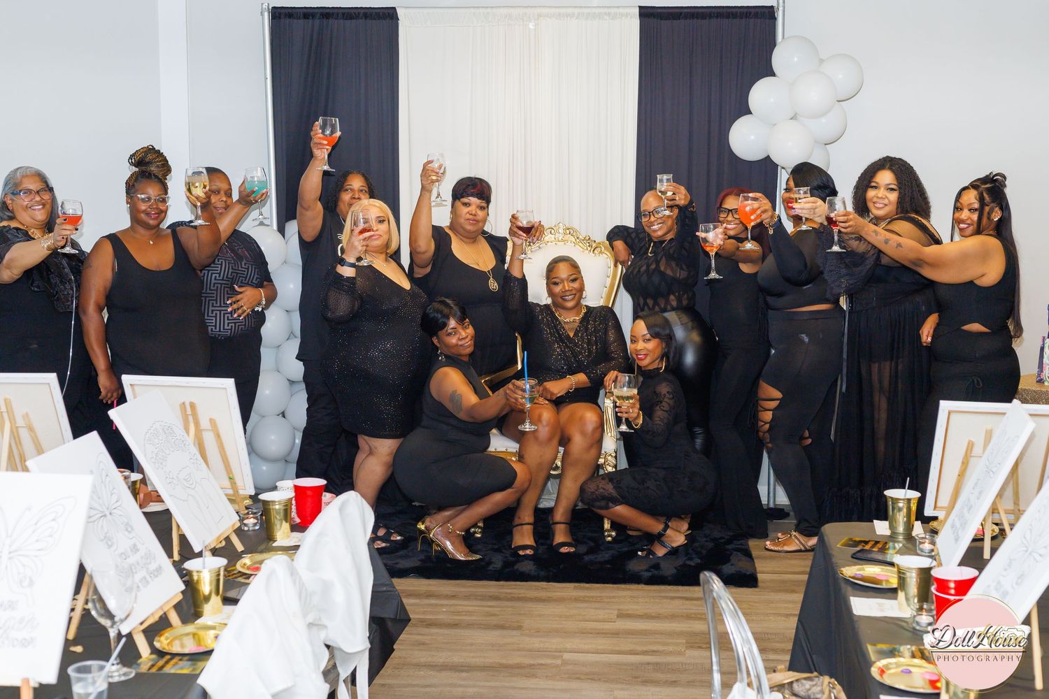 Group of women in black outfits raising glasses in a celebratory toast at a party event.