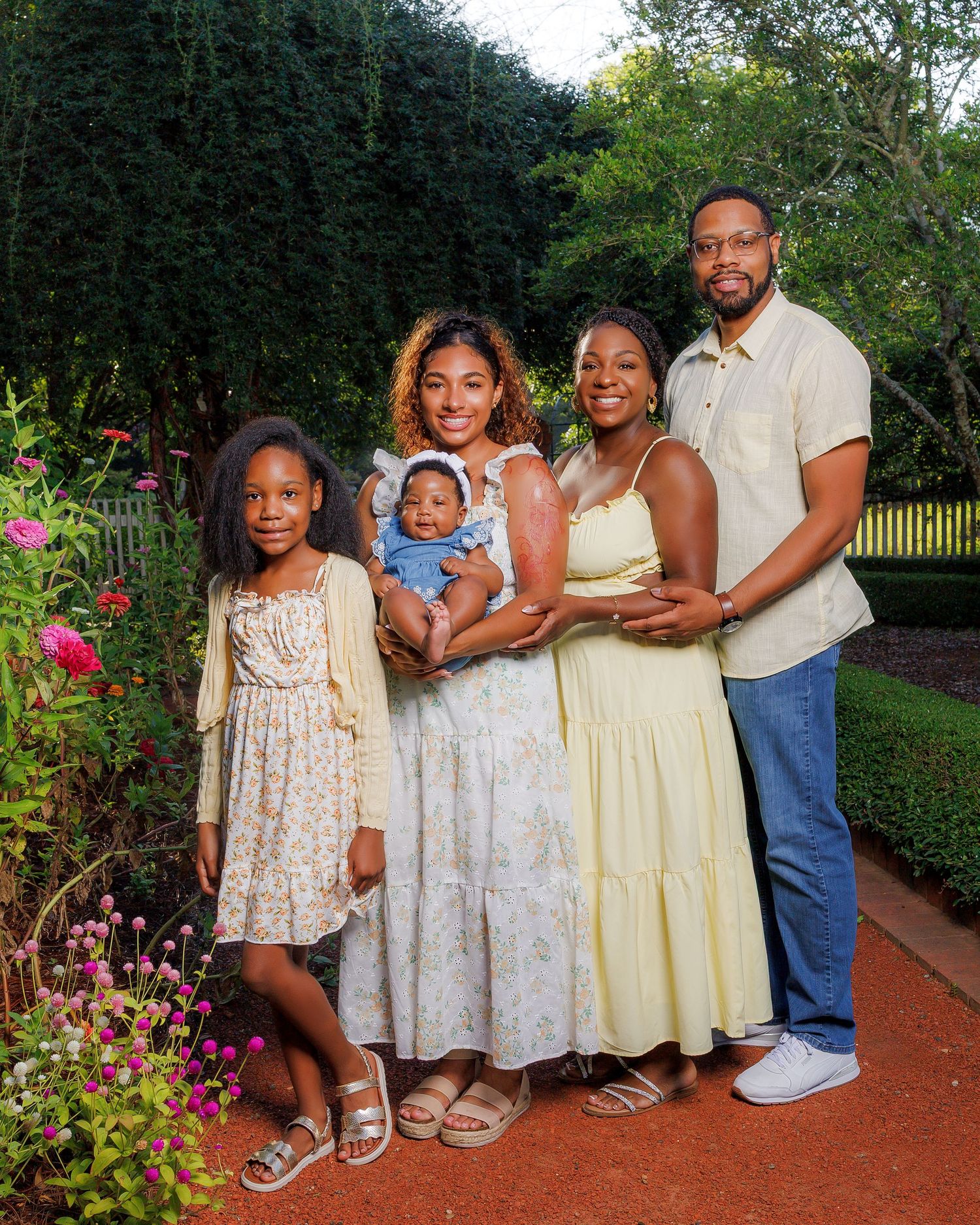Happy Black family of five posing together in a lush garden with flowers.