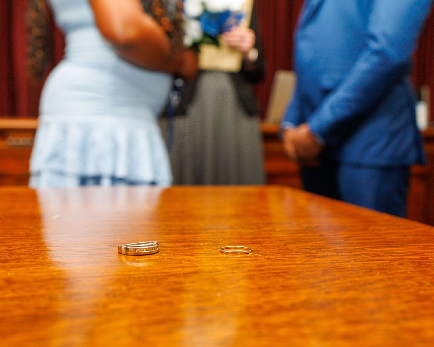 Two gold wedding rings on a wooden table during a courthouse wedding ceremony.