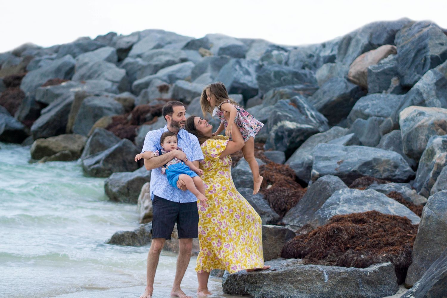 Group walking along rocky coastal shoreline during outdoor photo session.