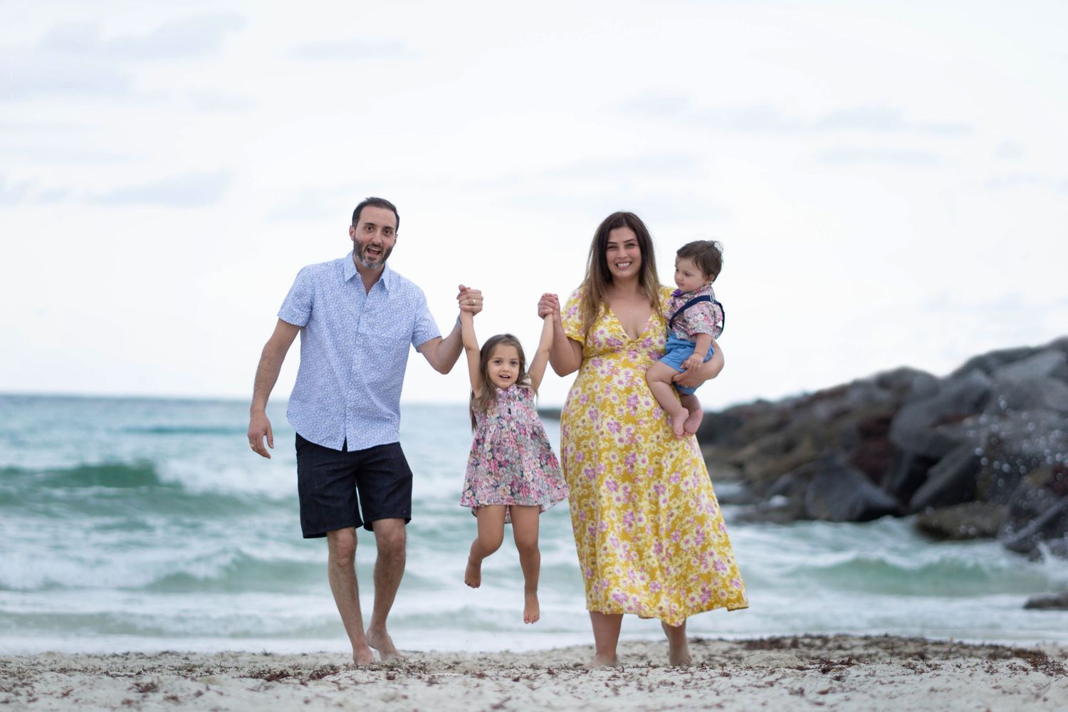 Family walking together on beach during sunset with ocean waves in background.