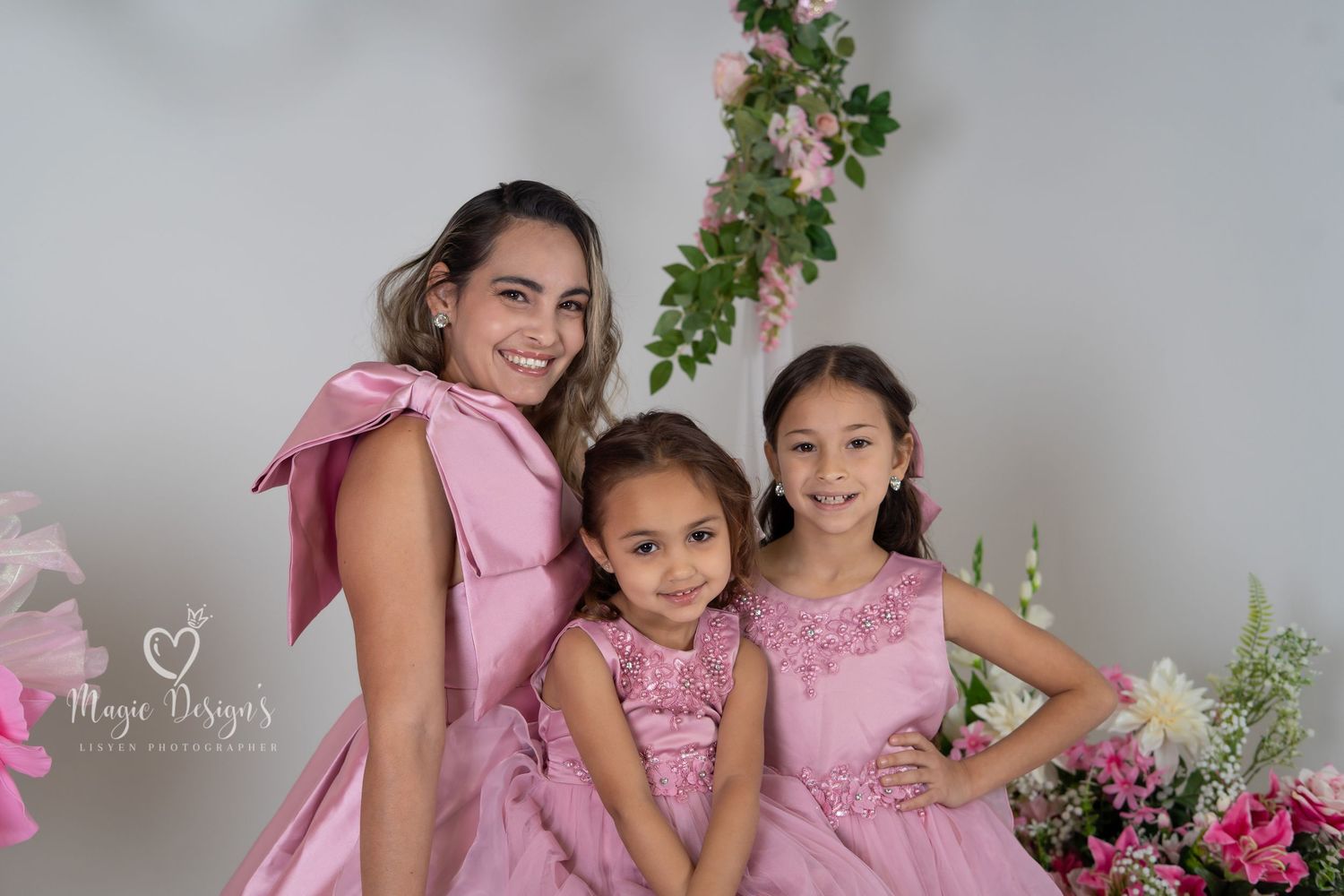 Sweet portrait session with matching pink dresses and floral decorative elements.