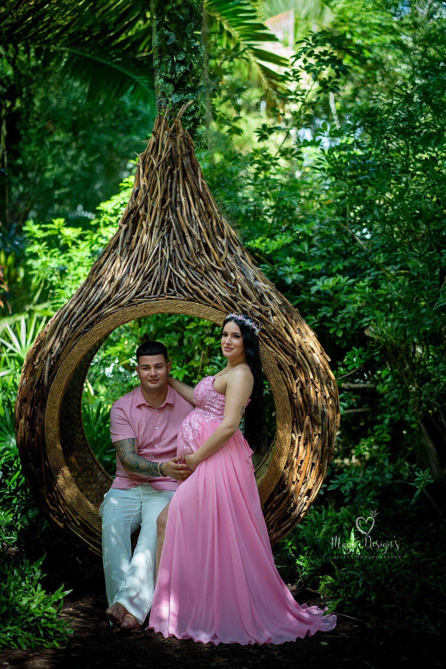 Romantic garden photoshoot with couple in pink dress inside woven wooden structure.