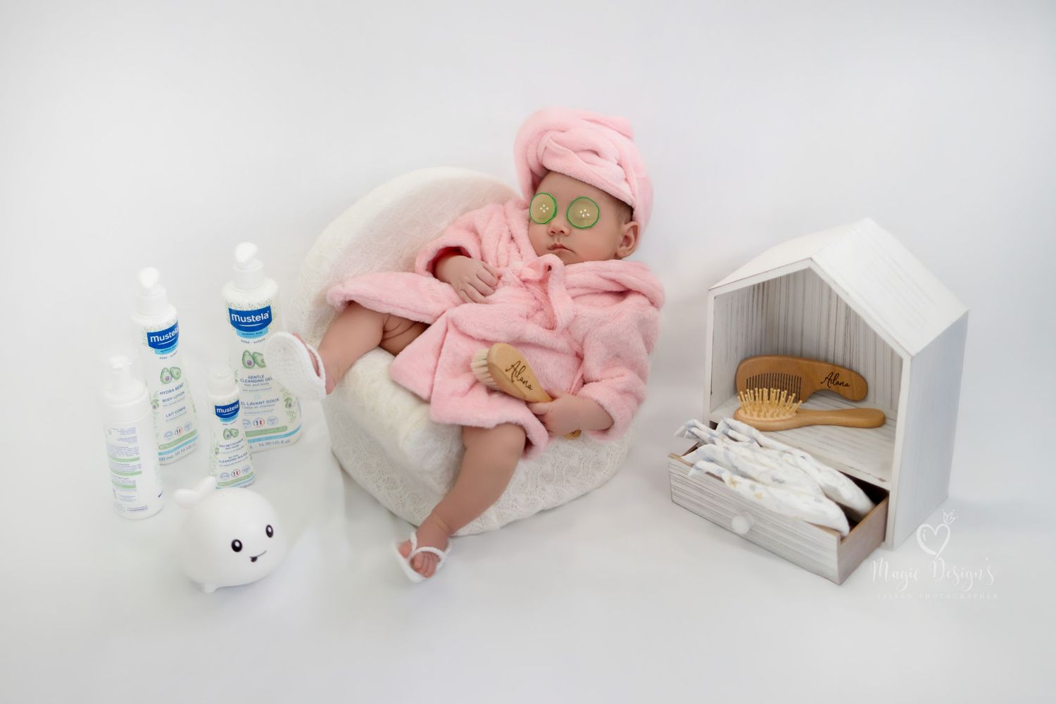 Minimalist newborn photography setup with pink accents and white medical props.