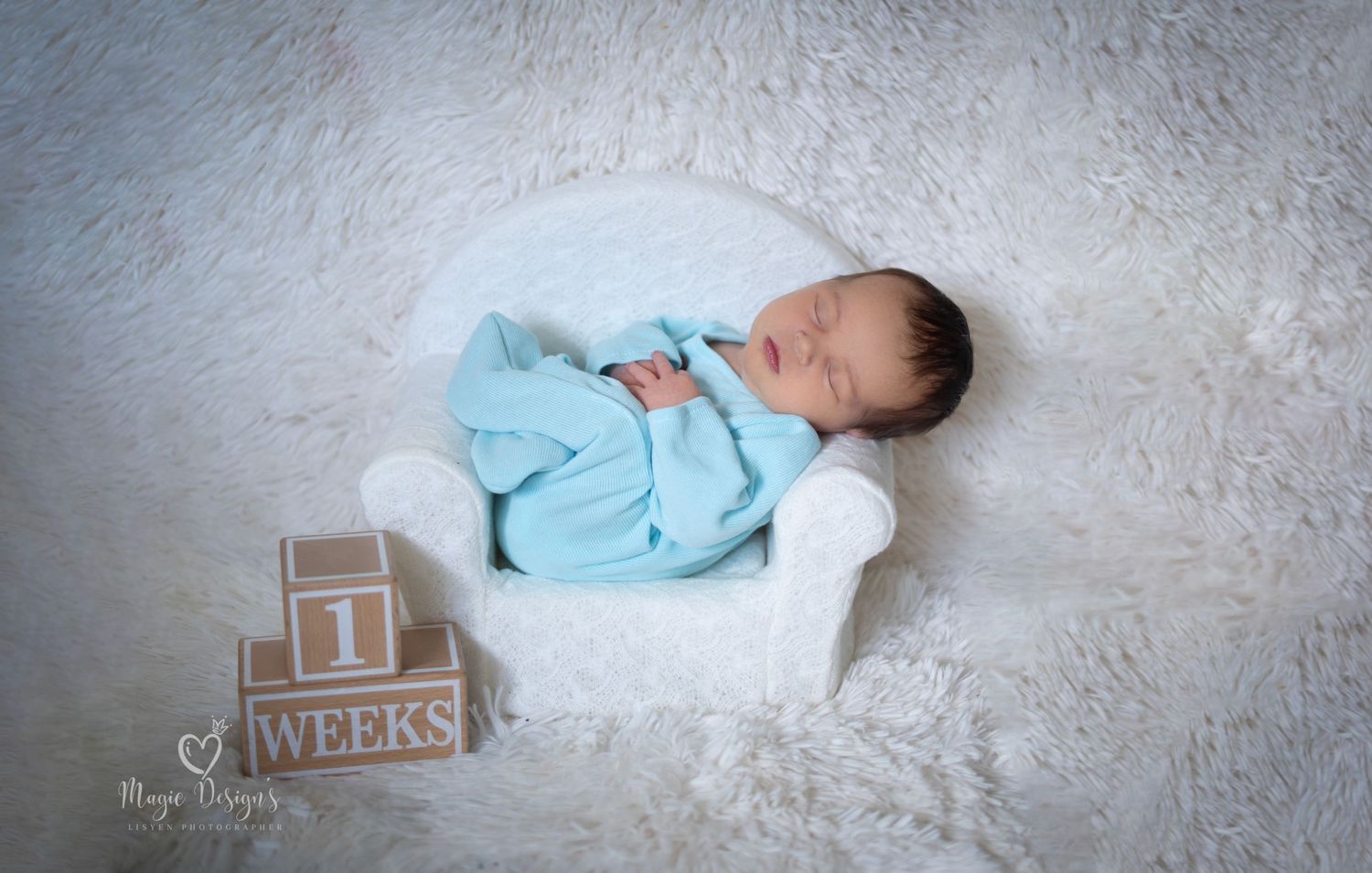 Professional newborn photography with blue blanket and milestone blocks on white background.