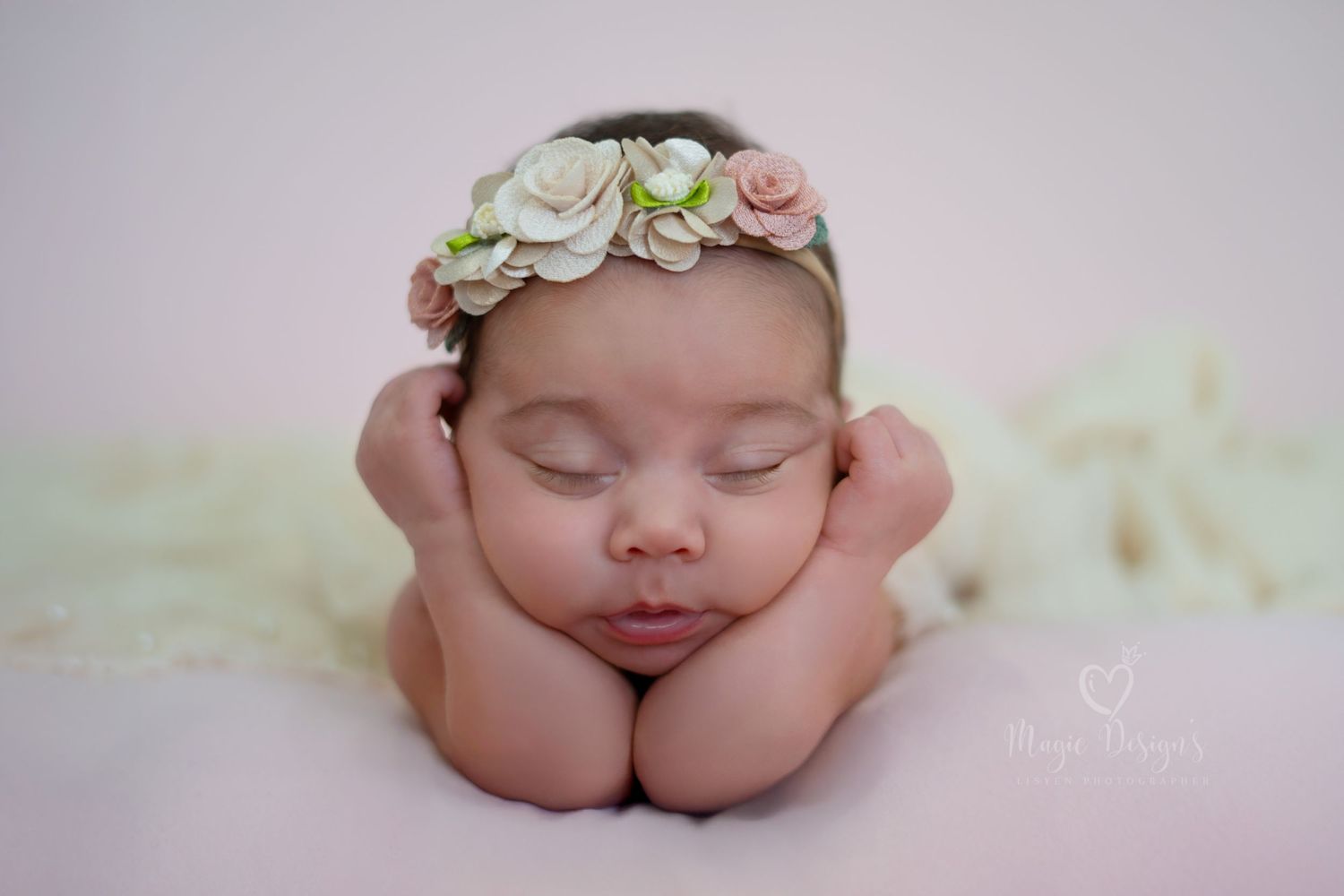 Delicate newborn portrait with floral headband against soft white background.