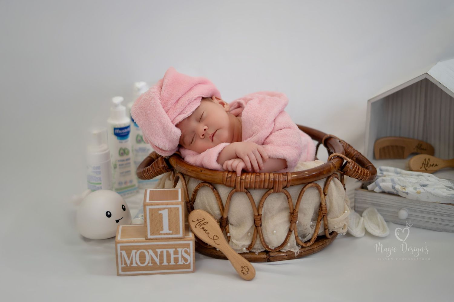 Baby milestone photoshoot with wooden blocks and pink elements on gray background.