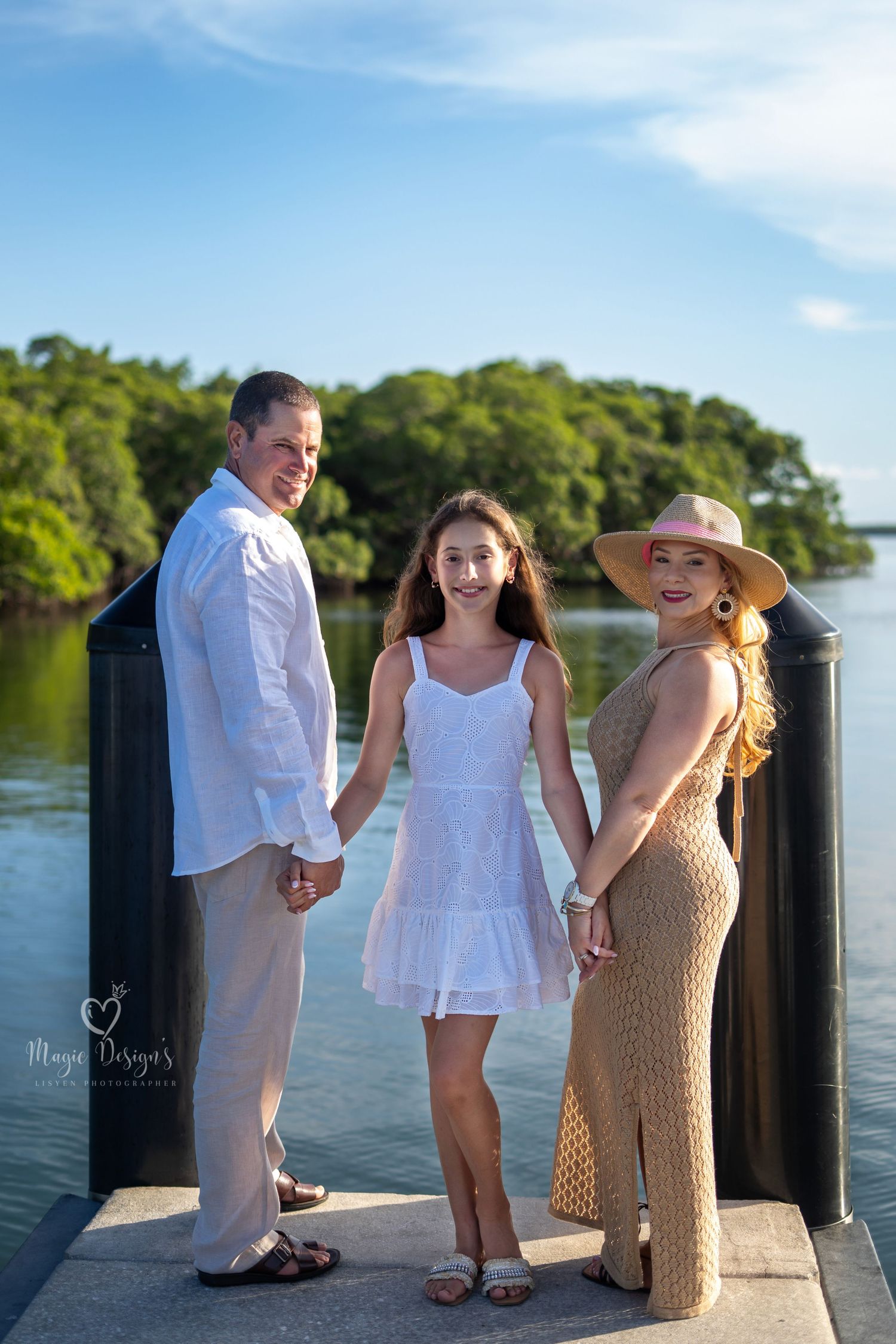 Group poses on wooden dock during golden hour with water and trees in background.