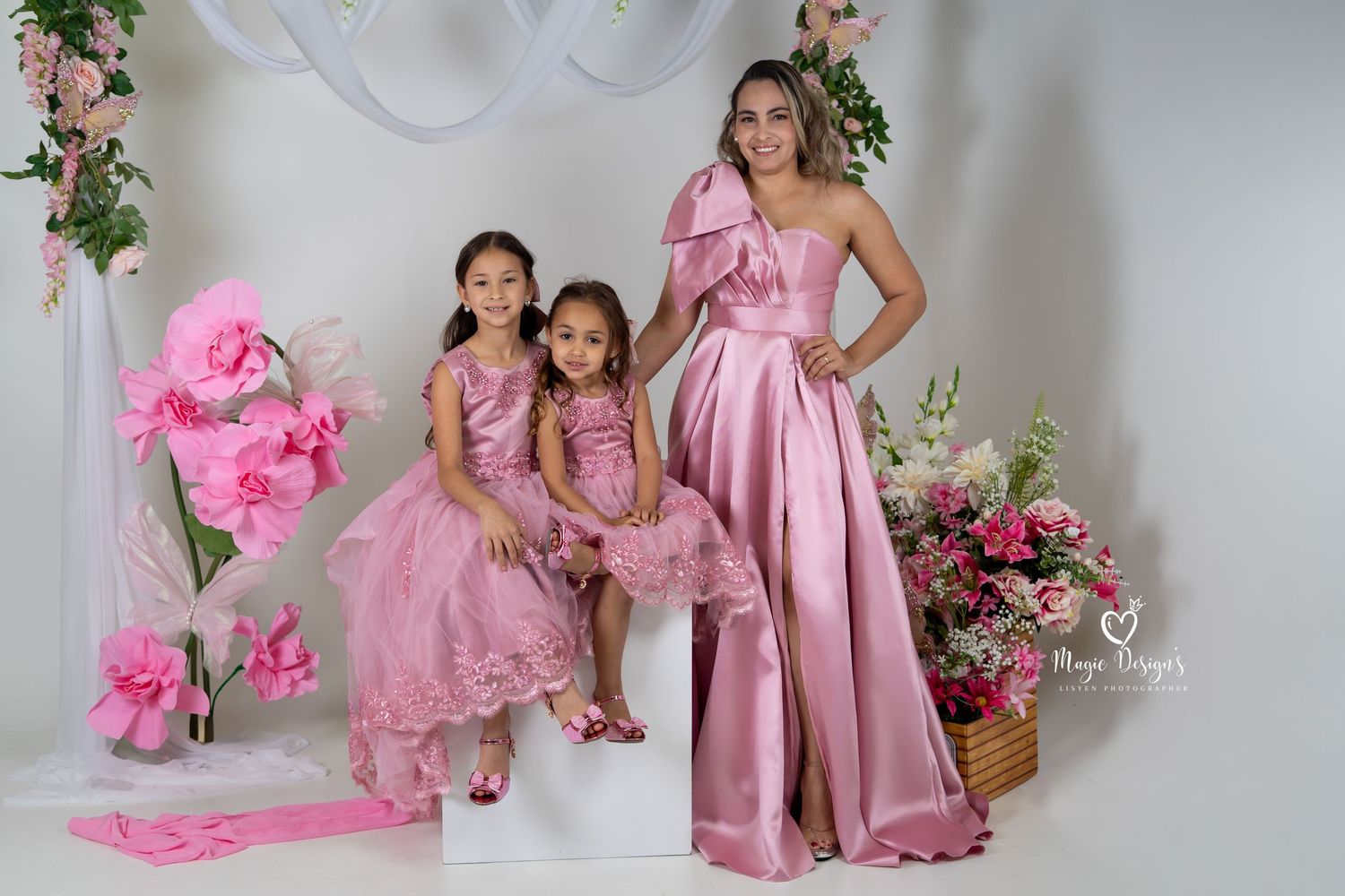 Elegant portrait featuring coordinated pink formal dresses with floral garden backdrop.