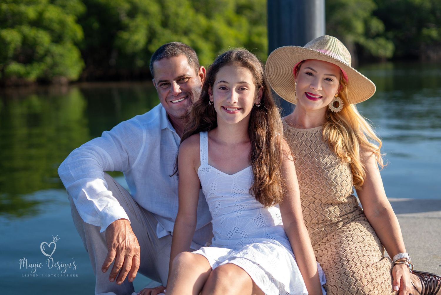 Family portrait session at sunset by waterfront with palm trees.