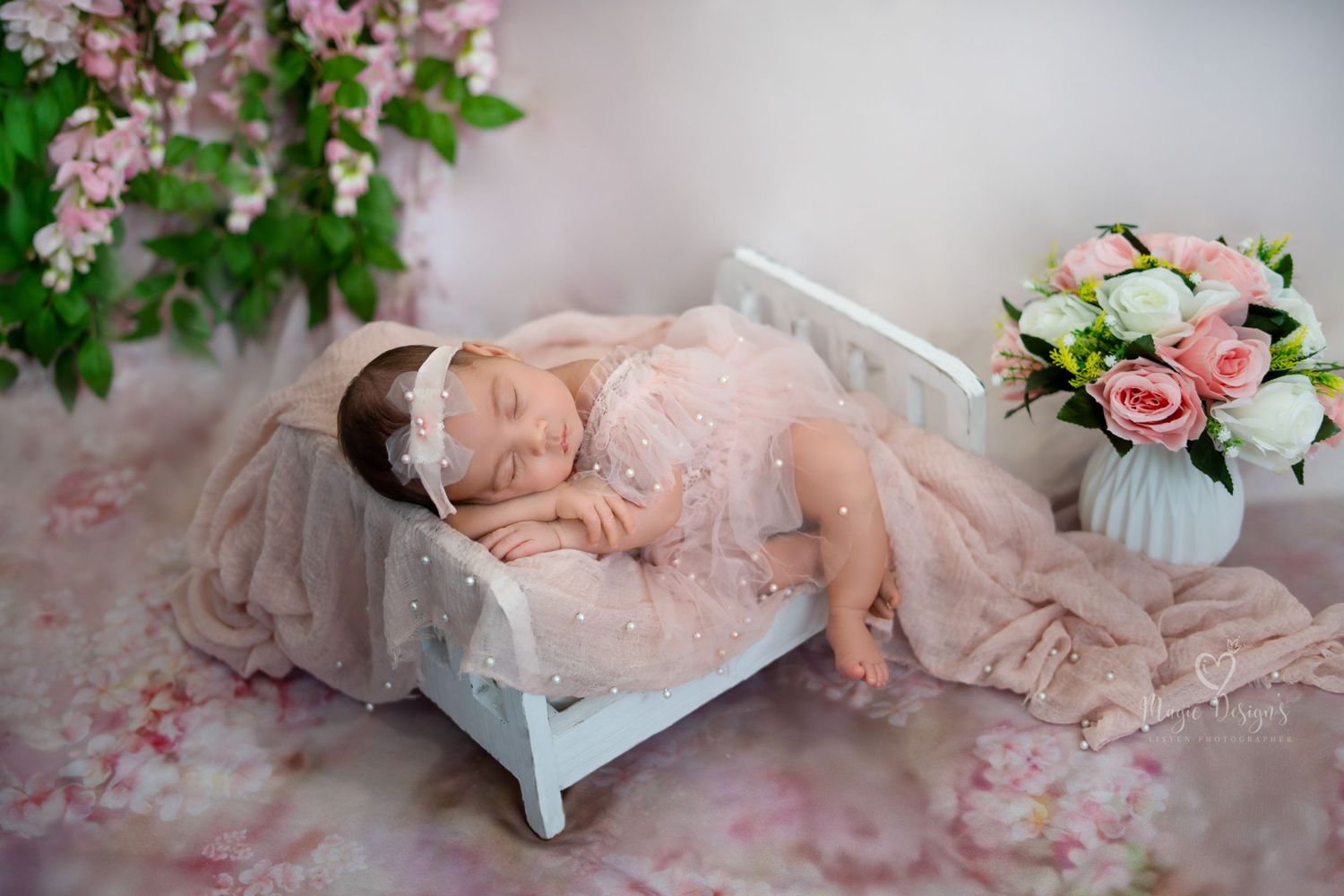 Dreamy newborn portrait with pink flowers and vintage decor in soft lighting.