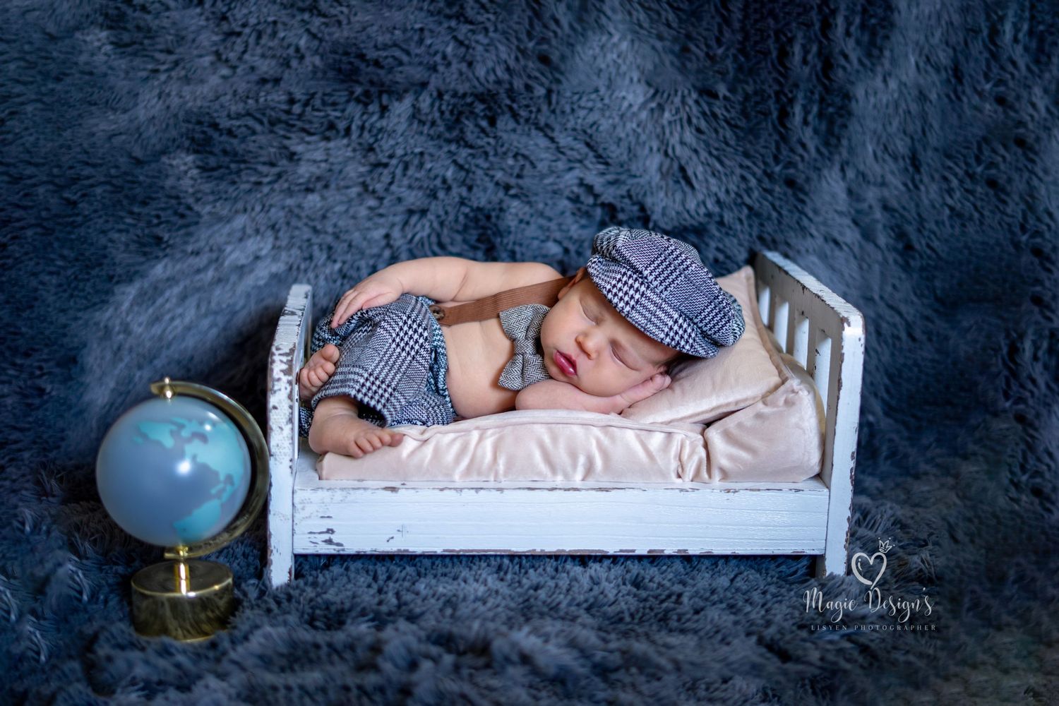 Creative newborn portrait session with navy backdrop and small white bed prop.