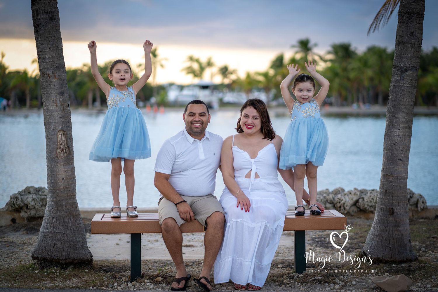 Family group poses together on beach at sunset wearing coordinated white outfits.