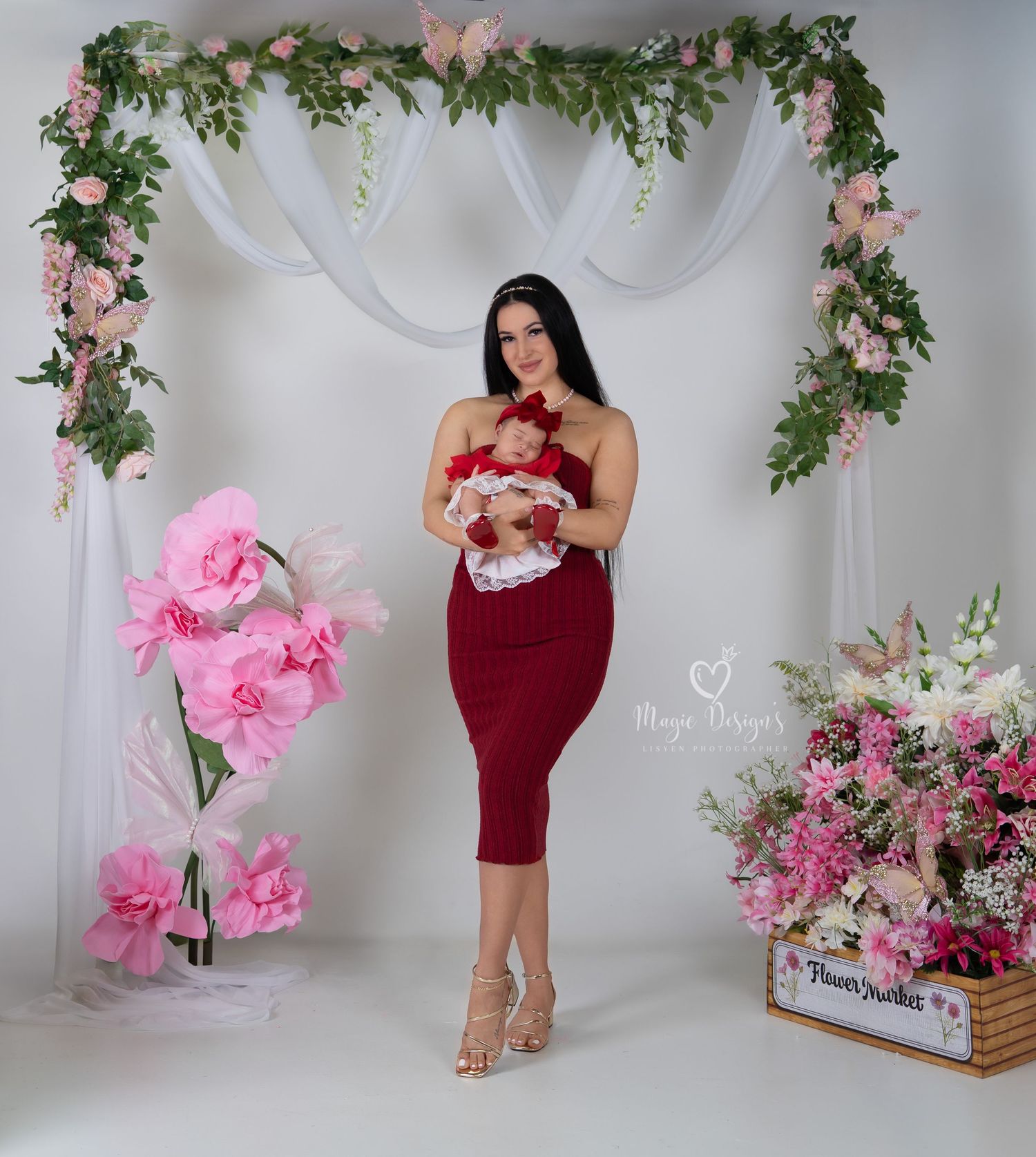 Romantic studio setup with floral decorations and pink accents against white backdrop.