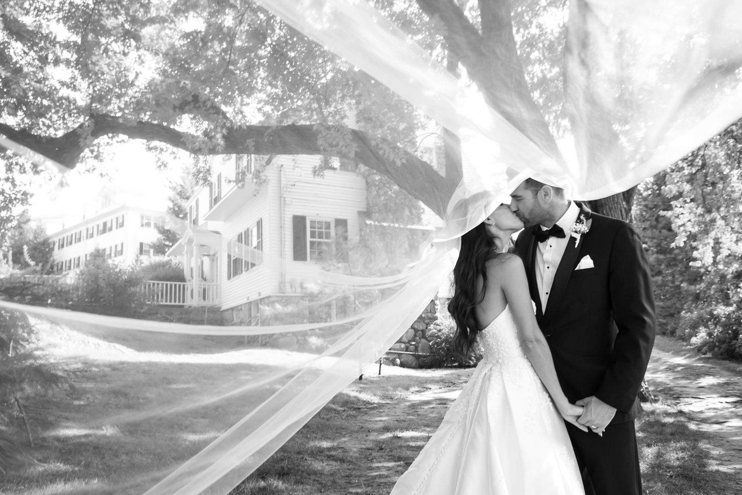 Romantic wedding couple portraits captured outdoors in a garden setting with a dreamy veil effect.