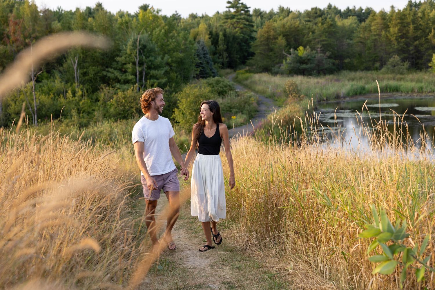 Engagement photos in tall grass field during golden hour.