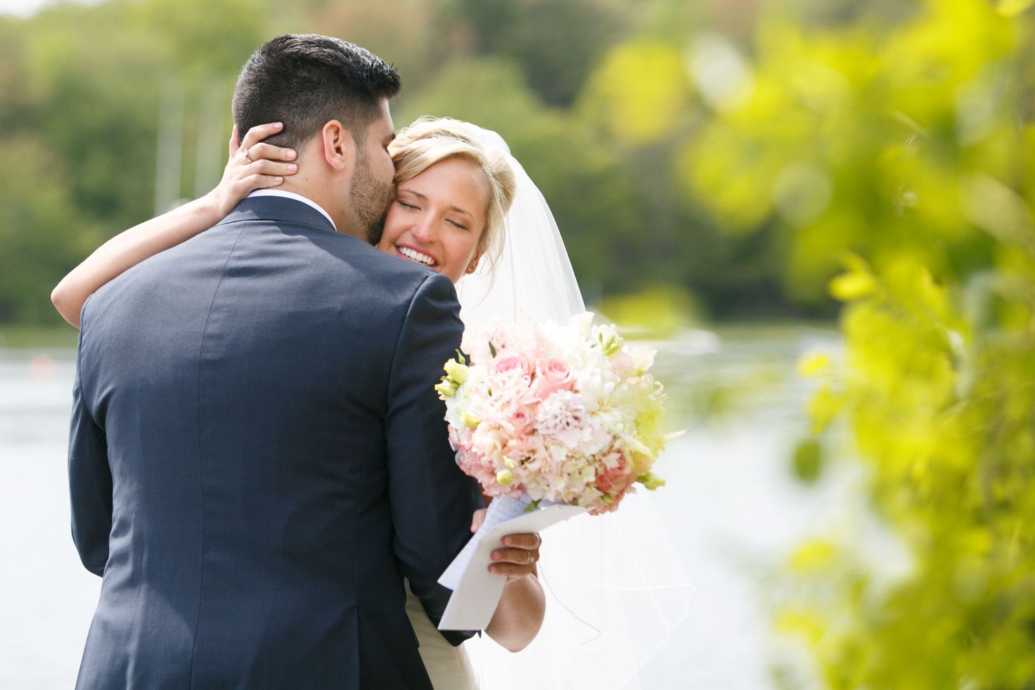 Tender wedding moments photographed in a sunlit garden with natural green foliage.