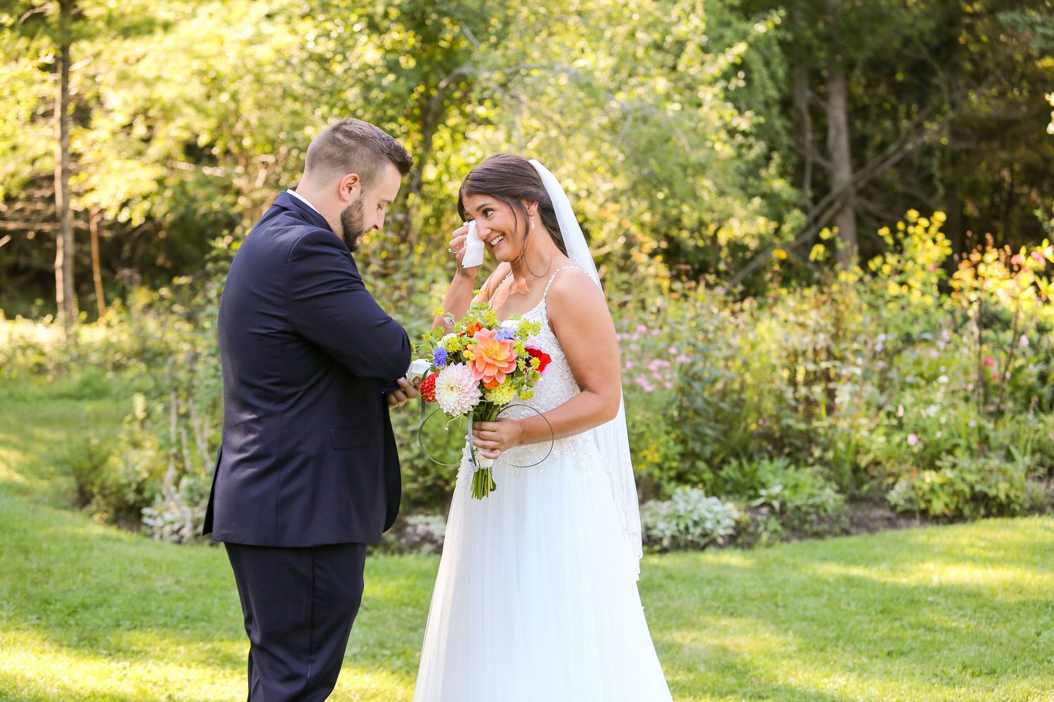 Wedding couple shares tender moment in sunlit garden setting.