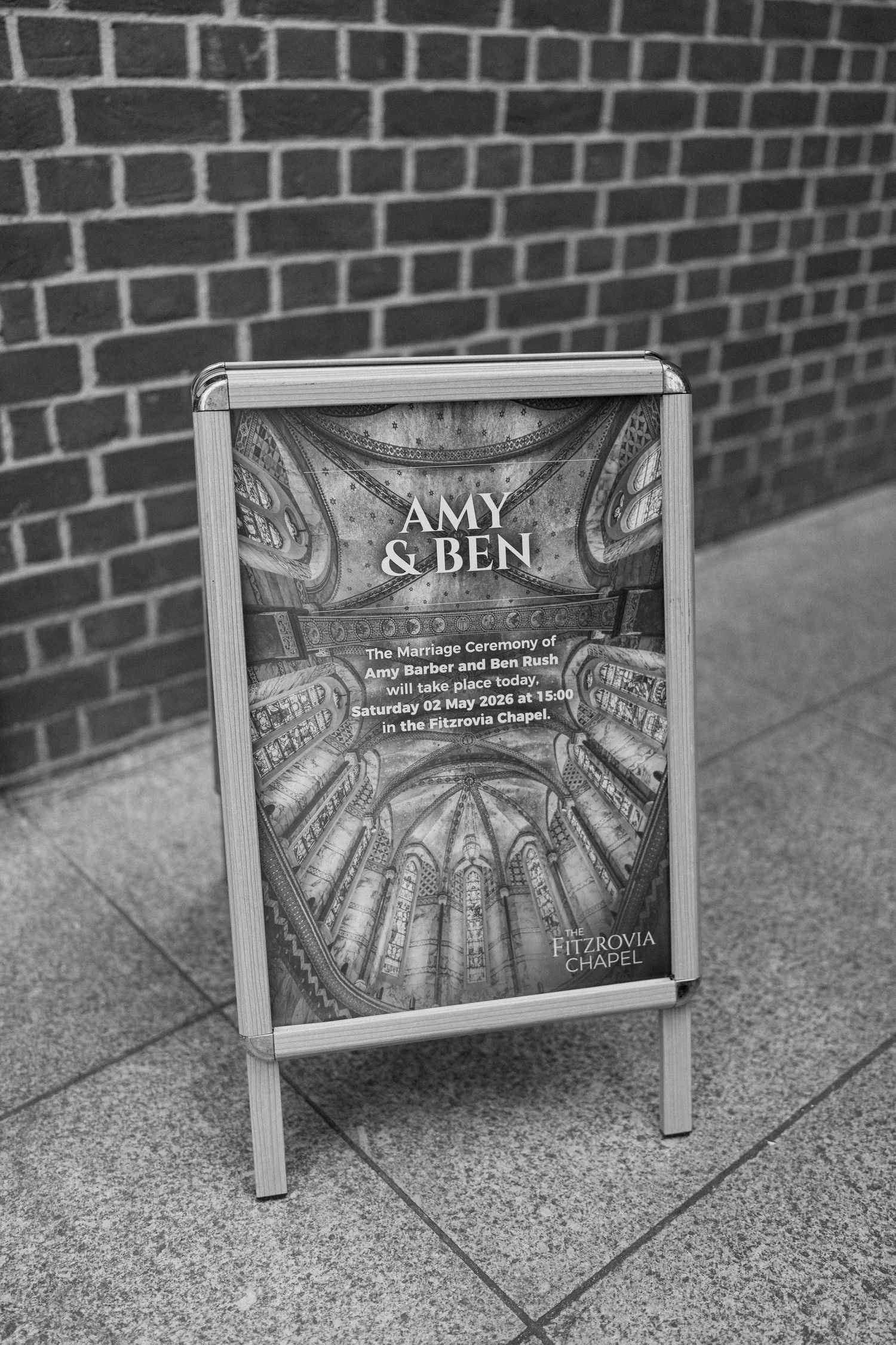 Black and white photo of a wedding sign for Amy and Ben at Fitzrovia Chapel dated May 2025.