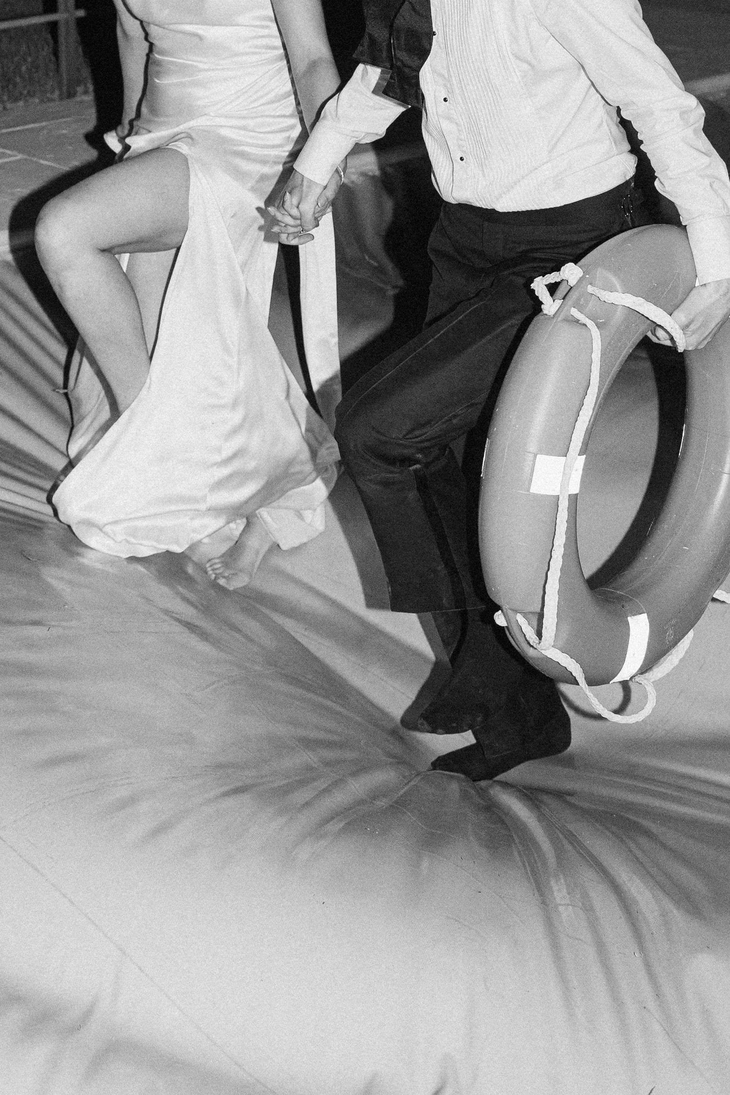 Black and white photo of couple holding hands with a life preserver ring at a wedding.