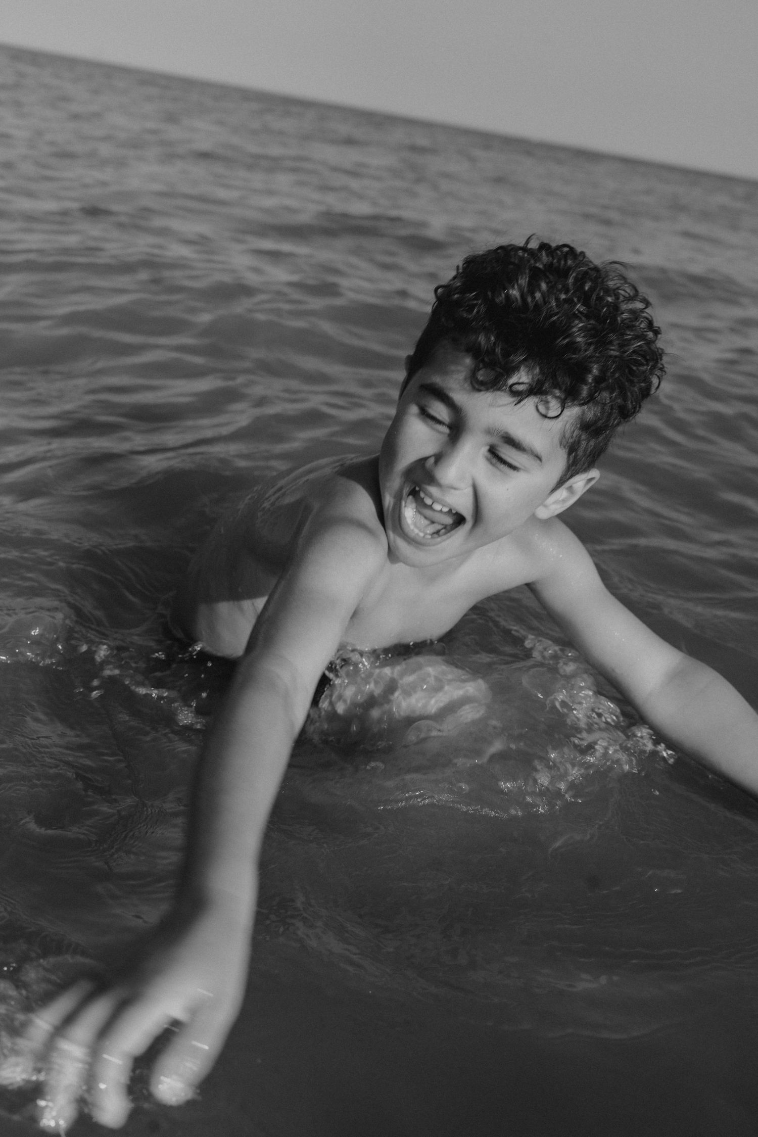 Child playing and splashing joyfully in ocean waves.