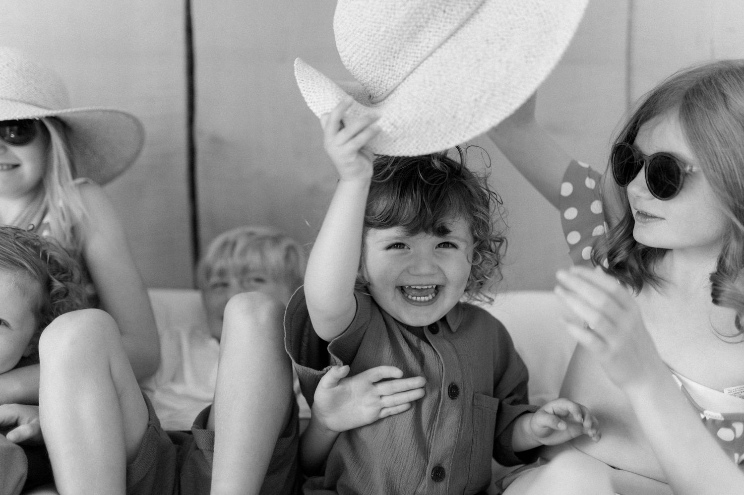 Series of black and white portraits showing playful moments with sun hats.