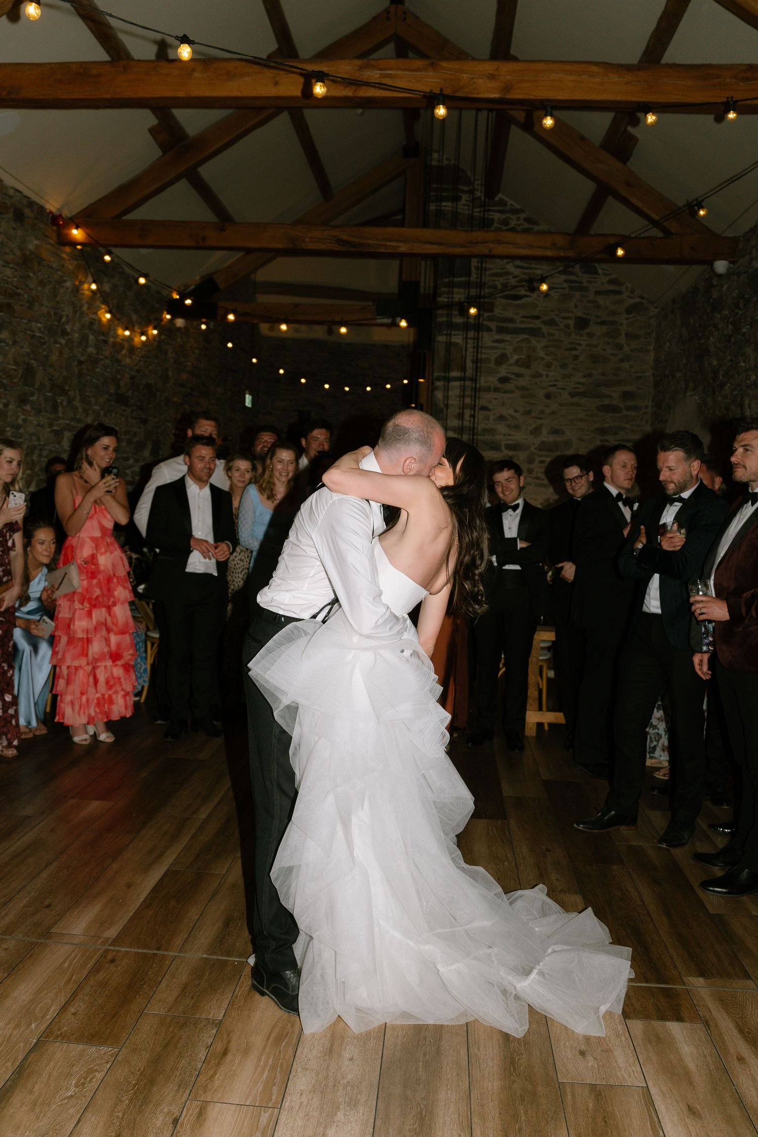 Couples share romantic dances on a wooden floor at a barn wedding reception.