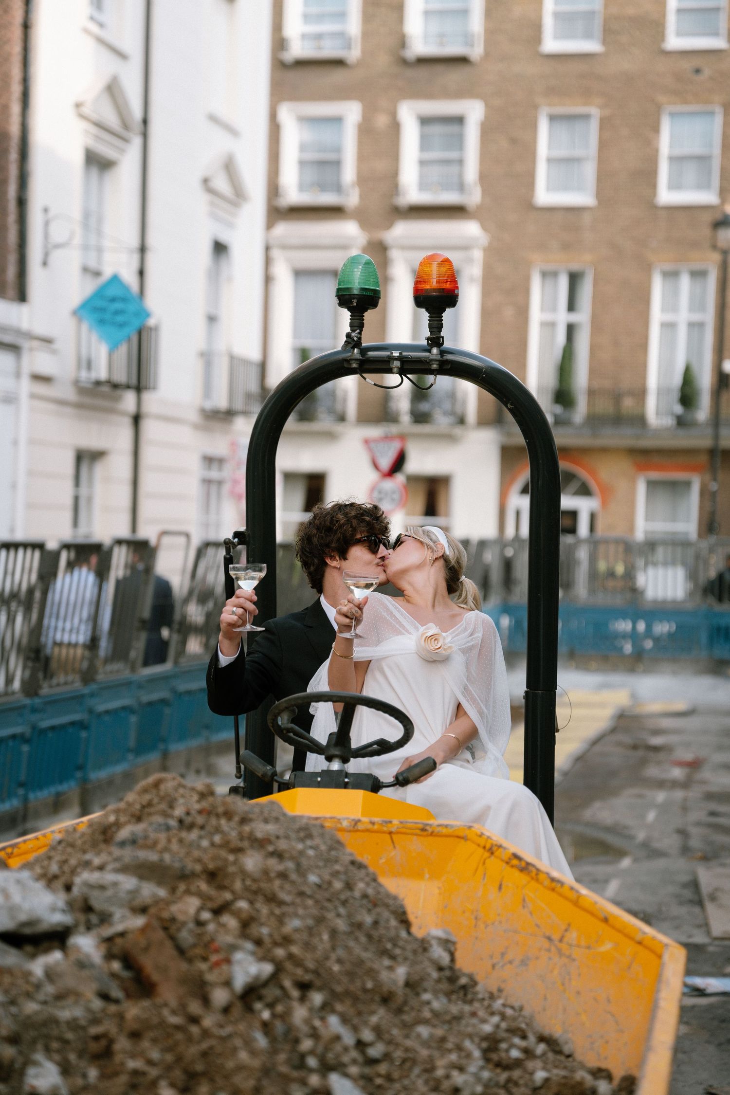 Wedding couple poses romantically in front of a construction vehicle on a city street.