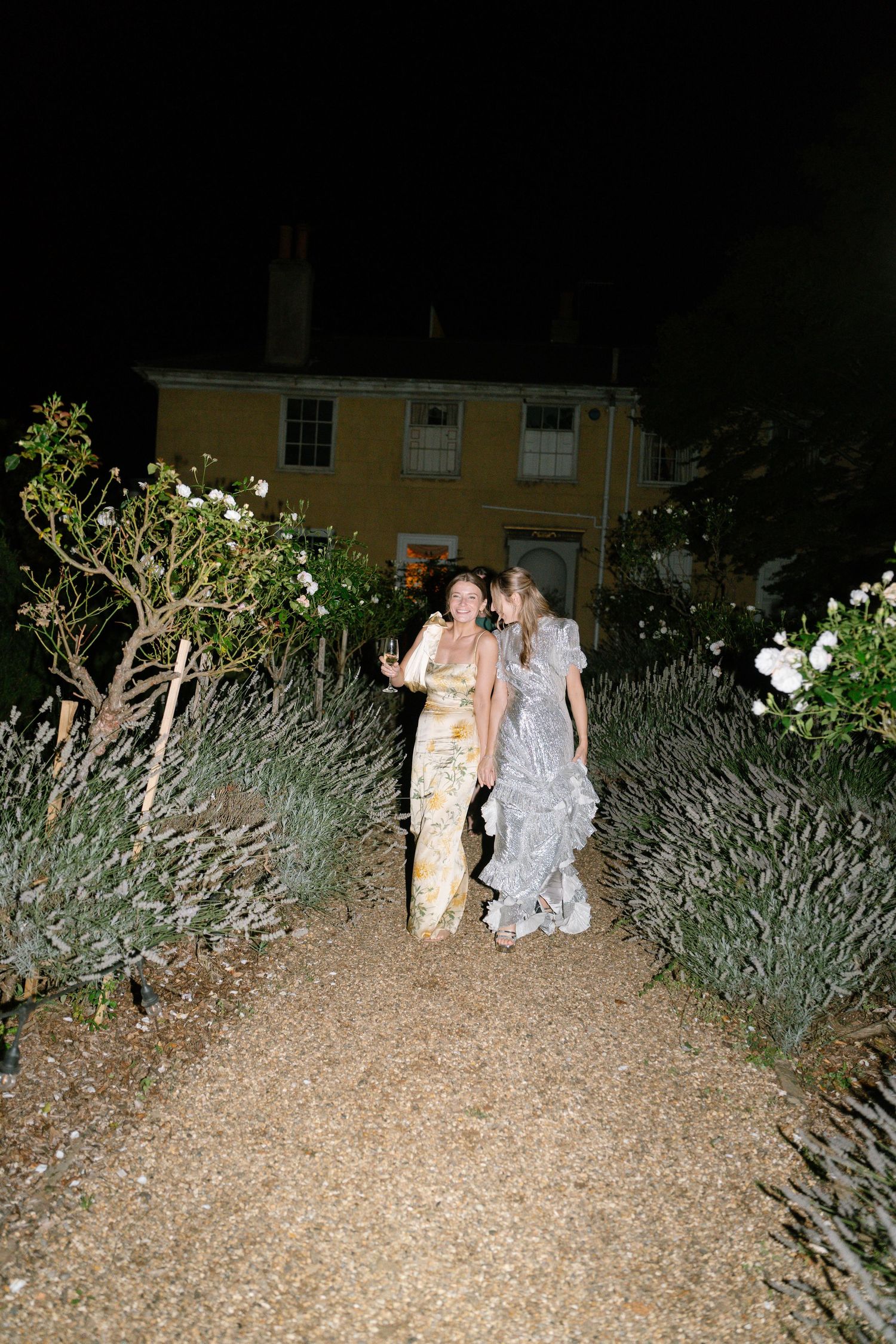 Evening outdoor photo of guests walking through garden landscaping at formal event.