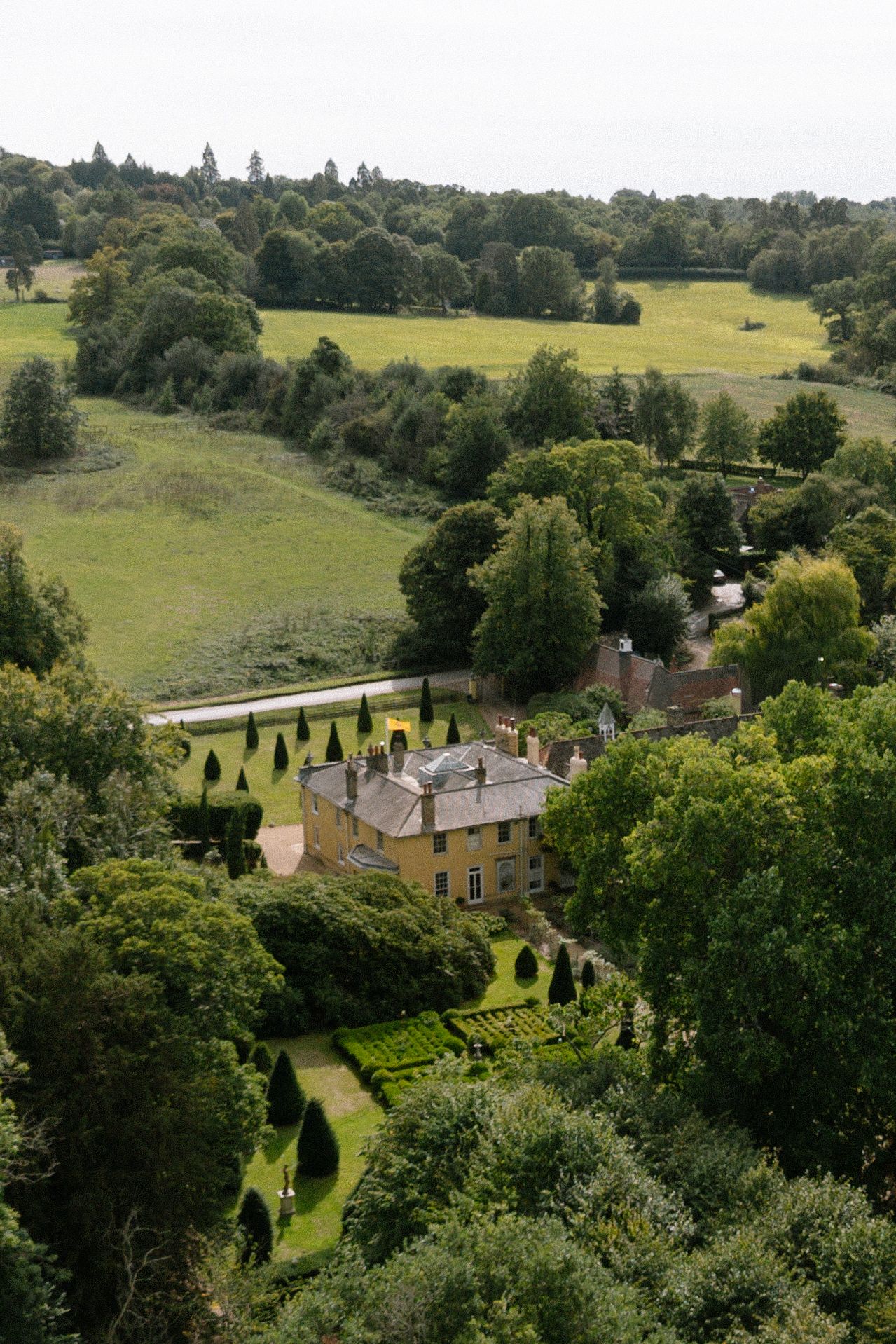 Aerial view of a grand estate surrounded by lush green gardens and countryside.