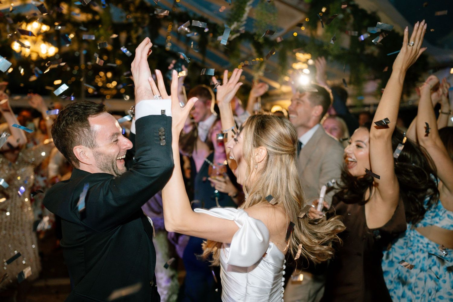 Lively dance floor scene with guests celebrating under warm lighting at a wedding reception.