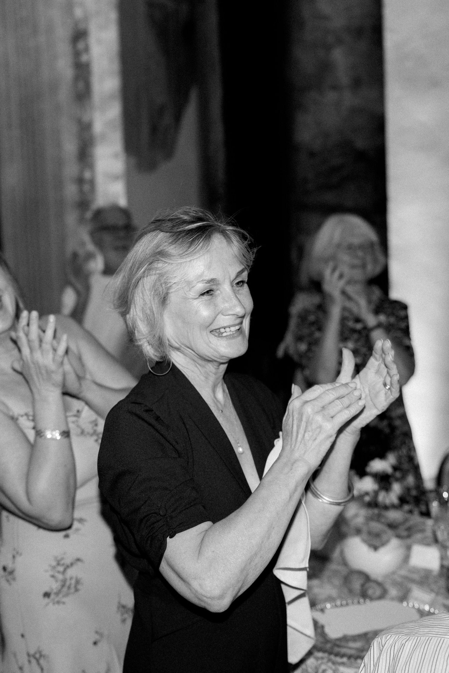 Guests applauding and celebrating at an elegant formal dinner event in black and white.
