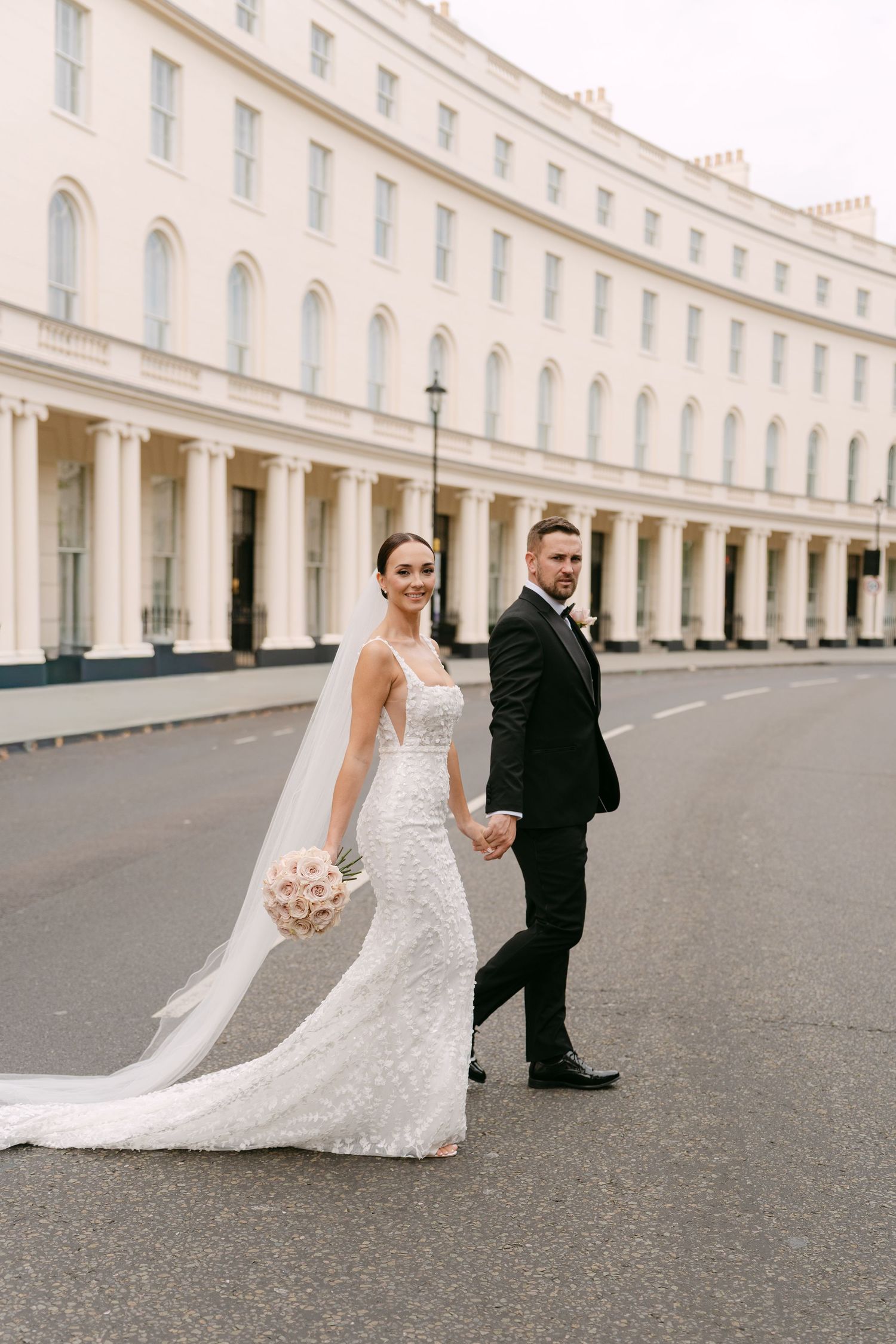 Elegant wedding couple poses on curved street with classic Georgian architecture.