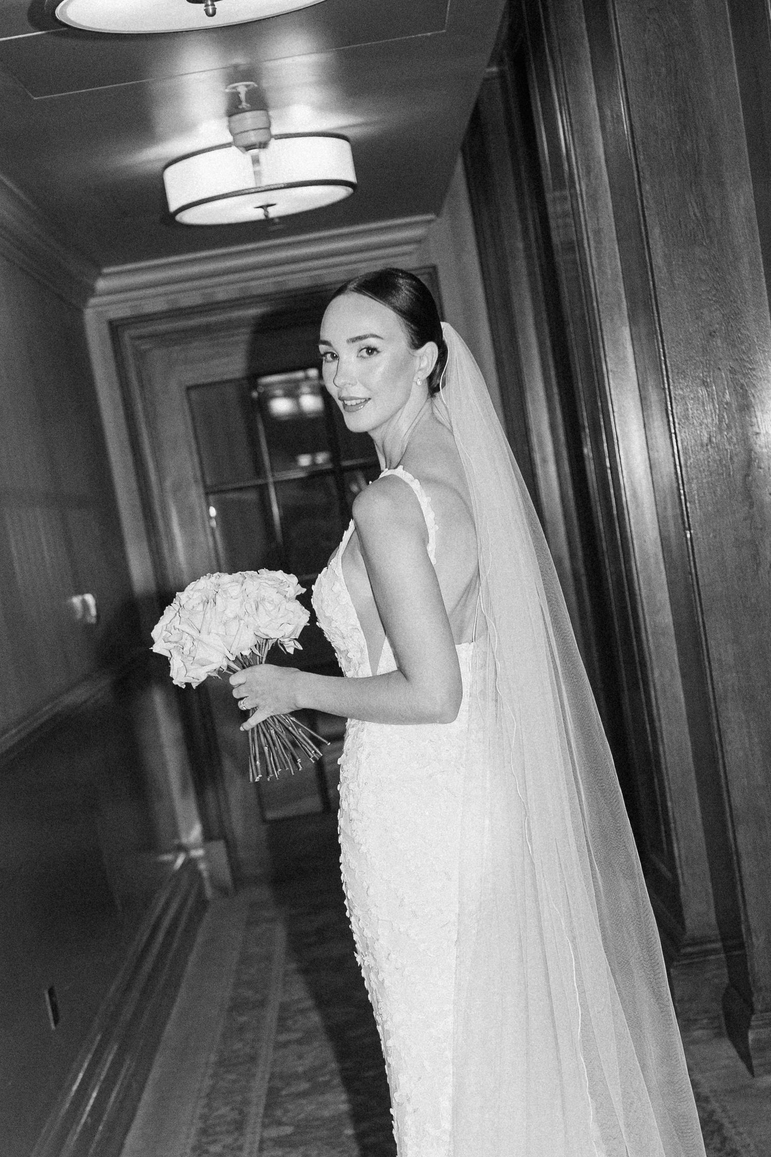 Black and white photos showing a bride with bouquet posing in an ornate hotel corridor.