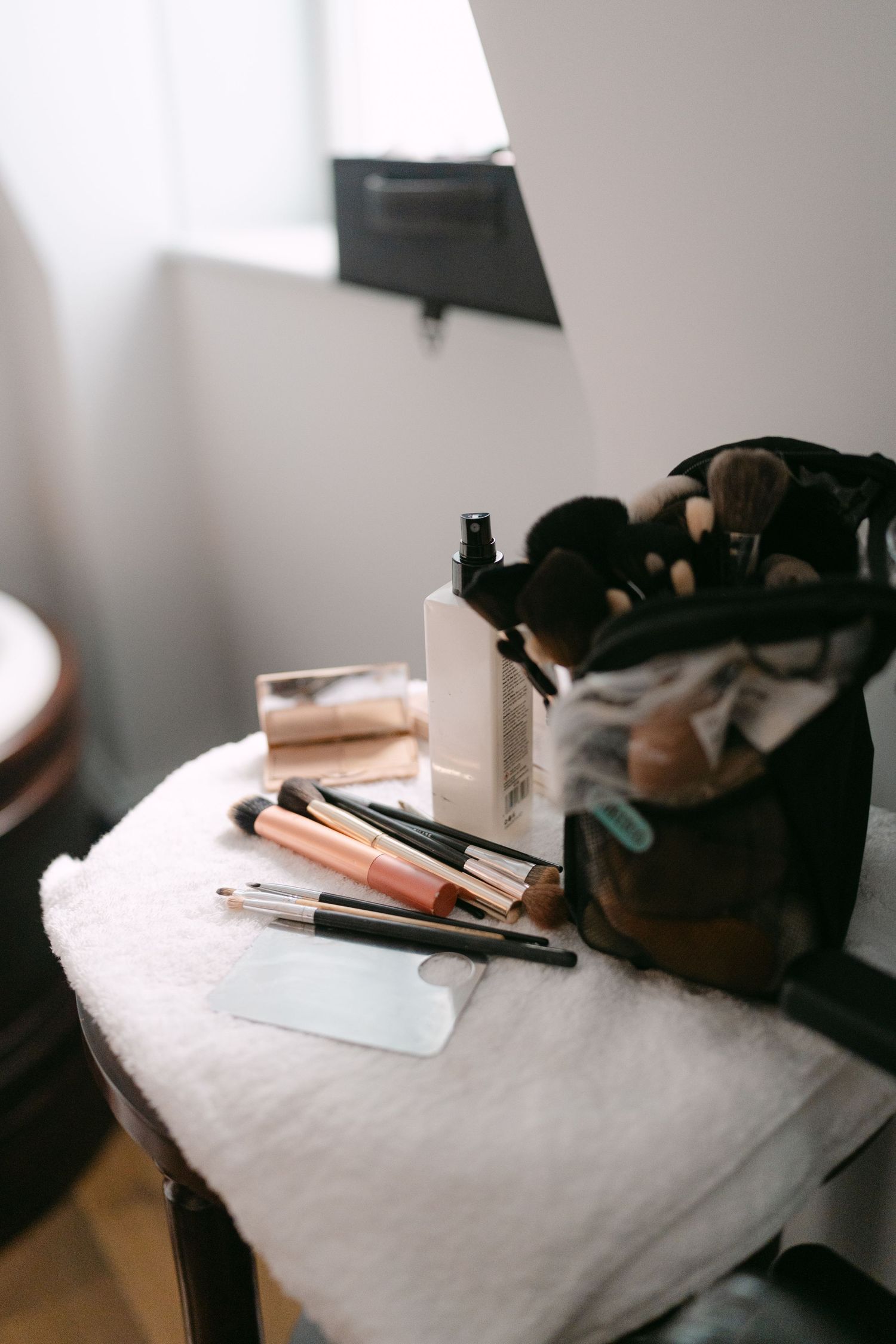 Makeup brushes and cosmetics arranged on white surface in morning light.