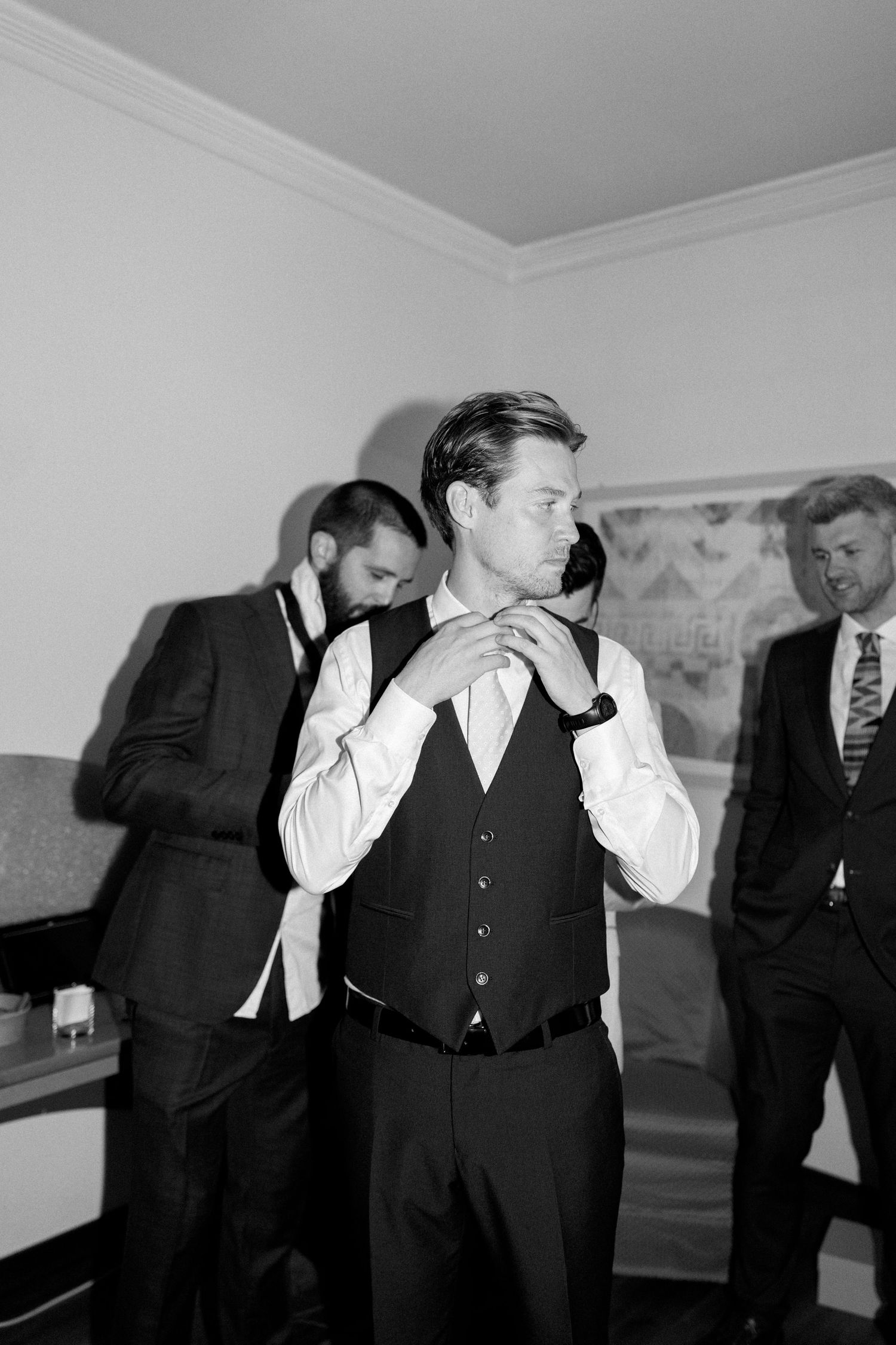 Men in dark suits and vests posing dramatically in black and white photo.