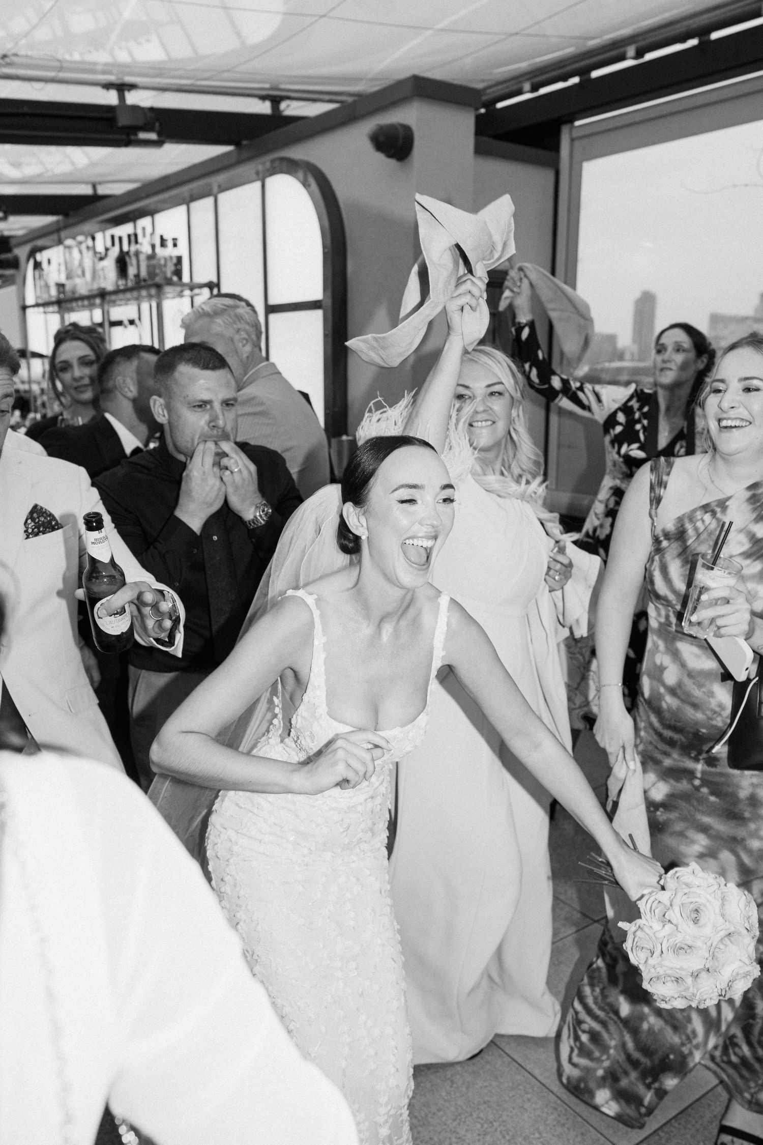 Wedding party celebrates with champagne toasts in a festive indoor setting.