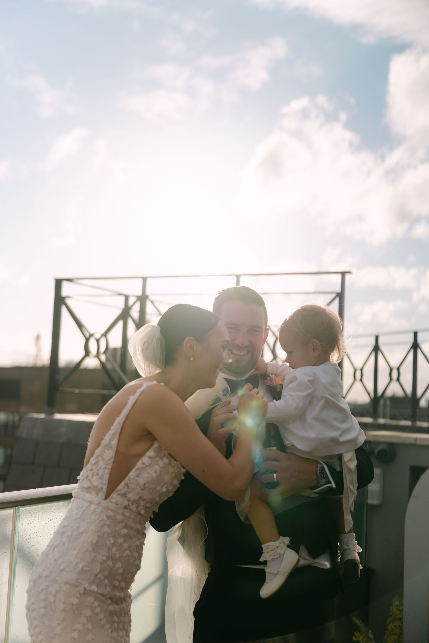 A tender family moment captured on a sunny rooftop with the bride in a lace dress.