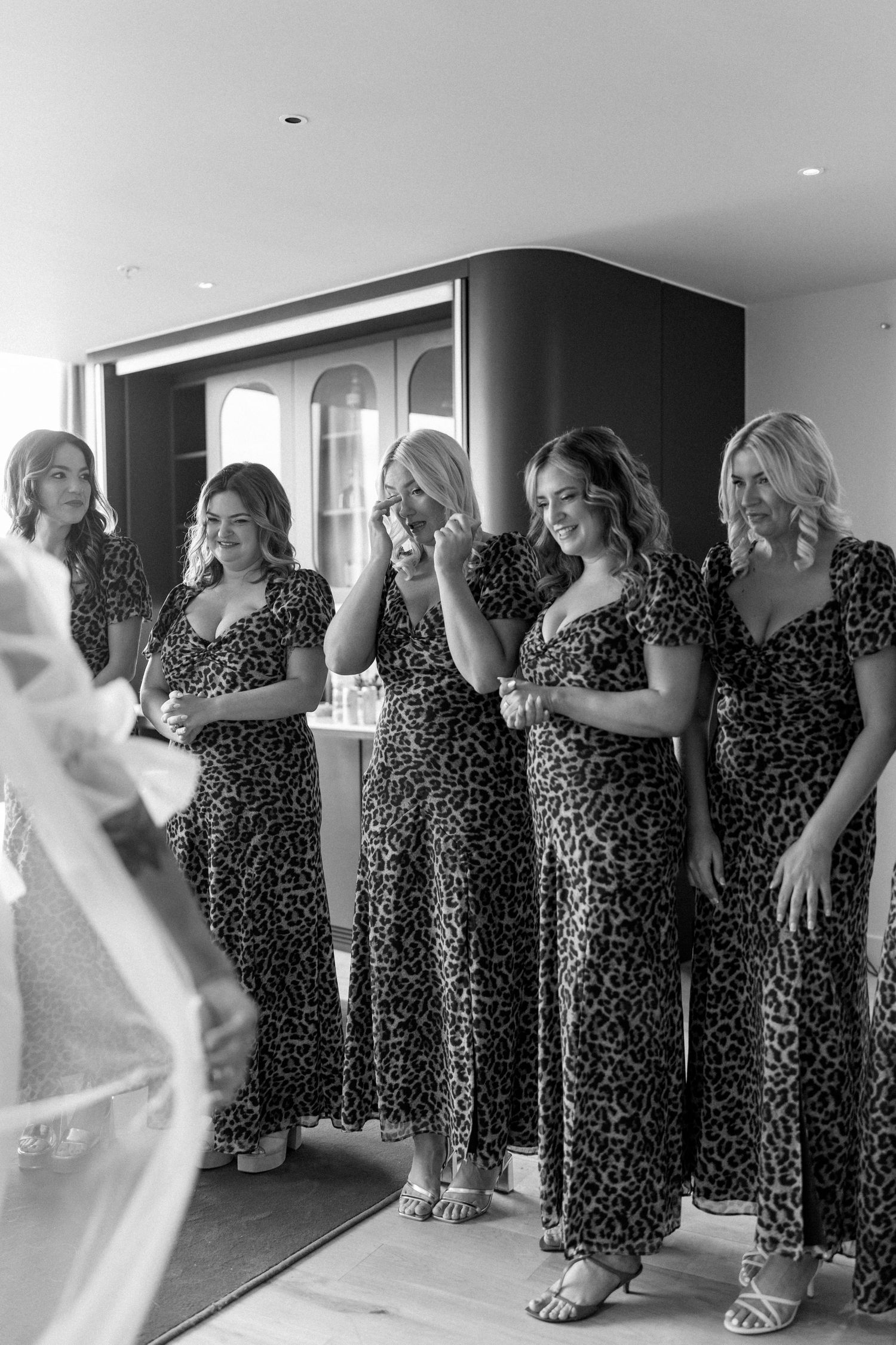 Bridesmaids in matching leopard print dresses react emotionally to seeing the bride.