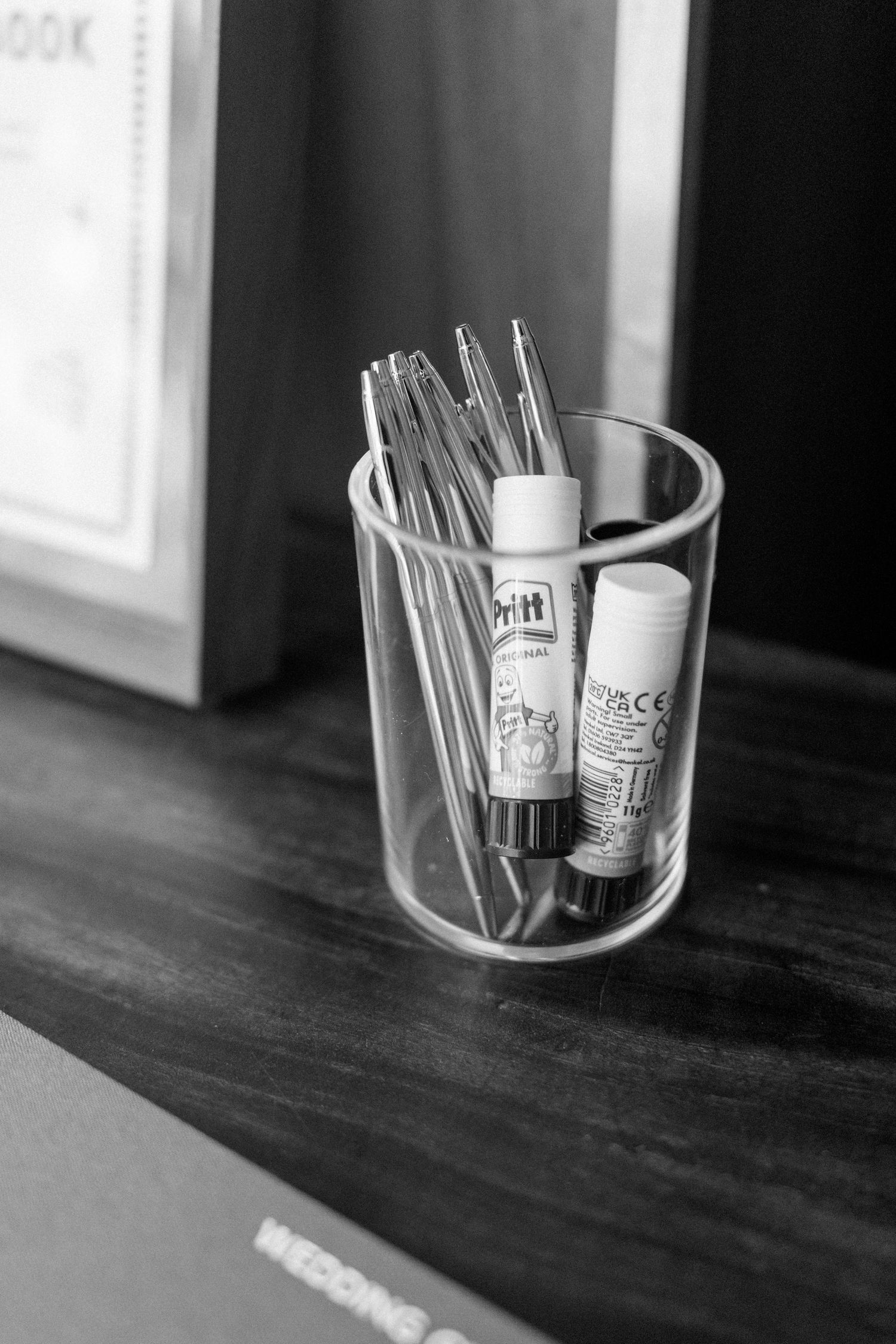 Black and white photo of drinking glasses and utensils arranged in a circular holder.