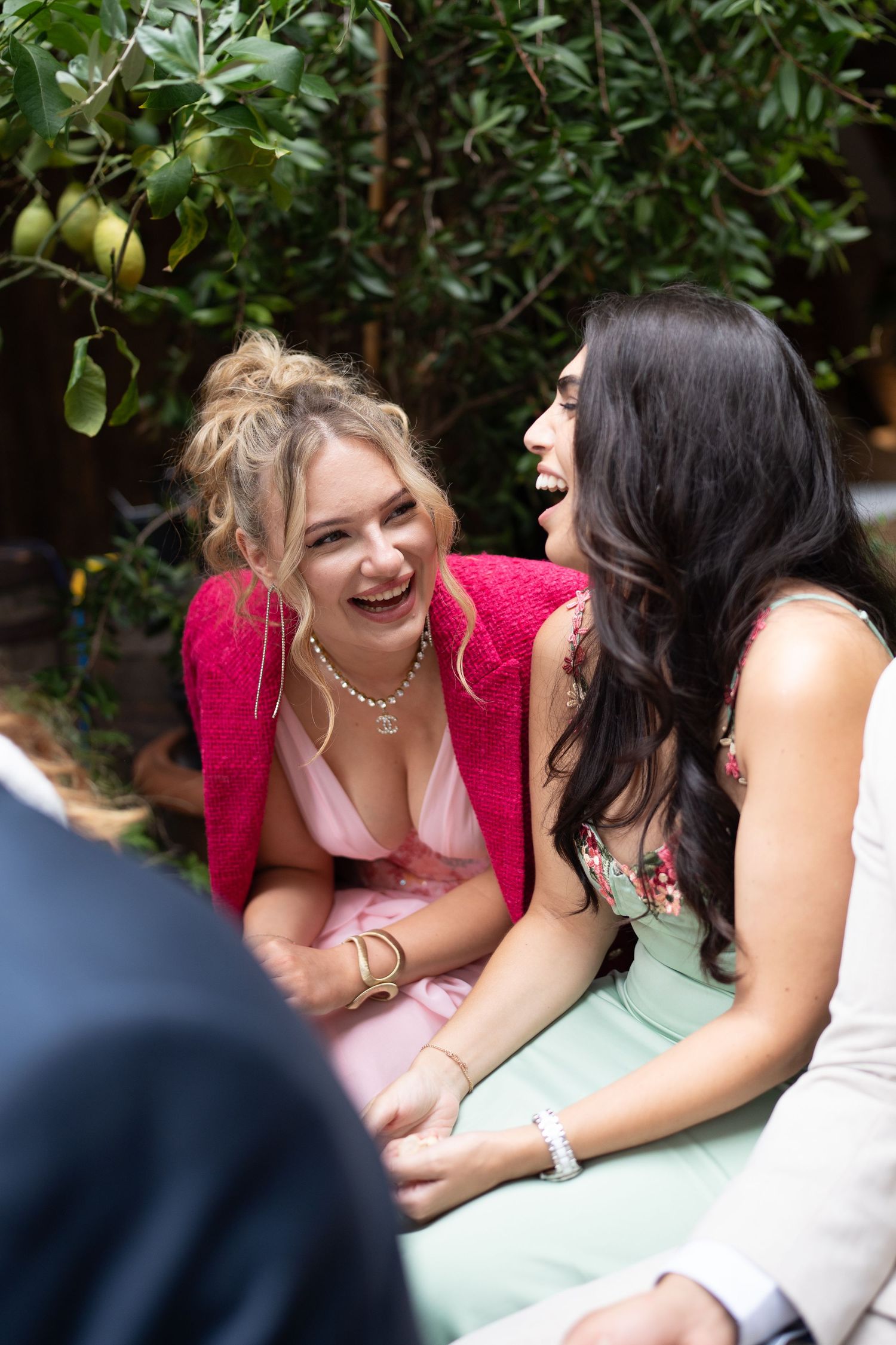 Two wedding guests sharing a laugh during outdoor reception.